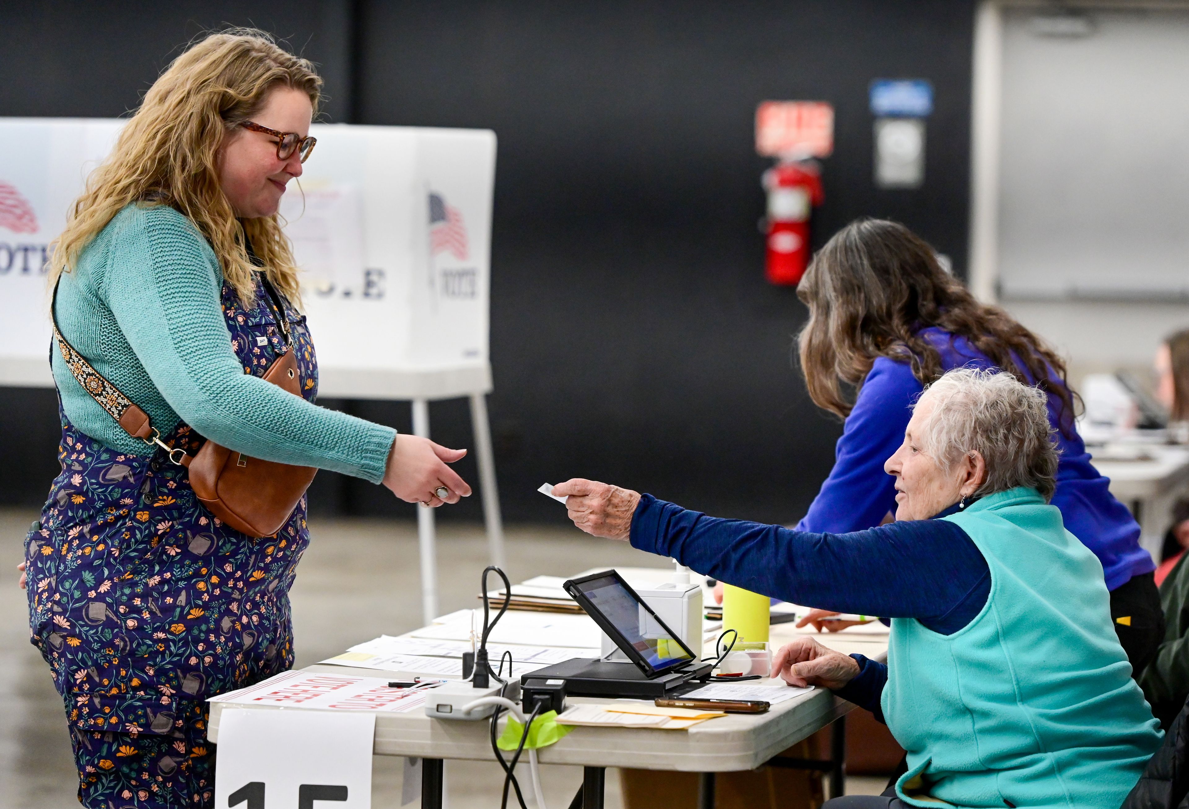 Ali Tong, left, provides identification to election judge Gail Cochran to receive a ballot at the Latah County Fairgrounds in Moscow on Election Day.