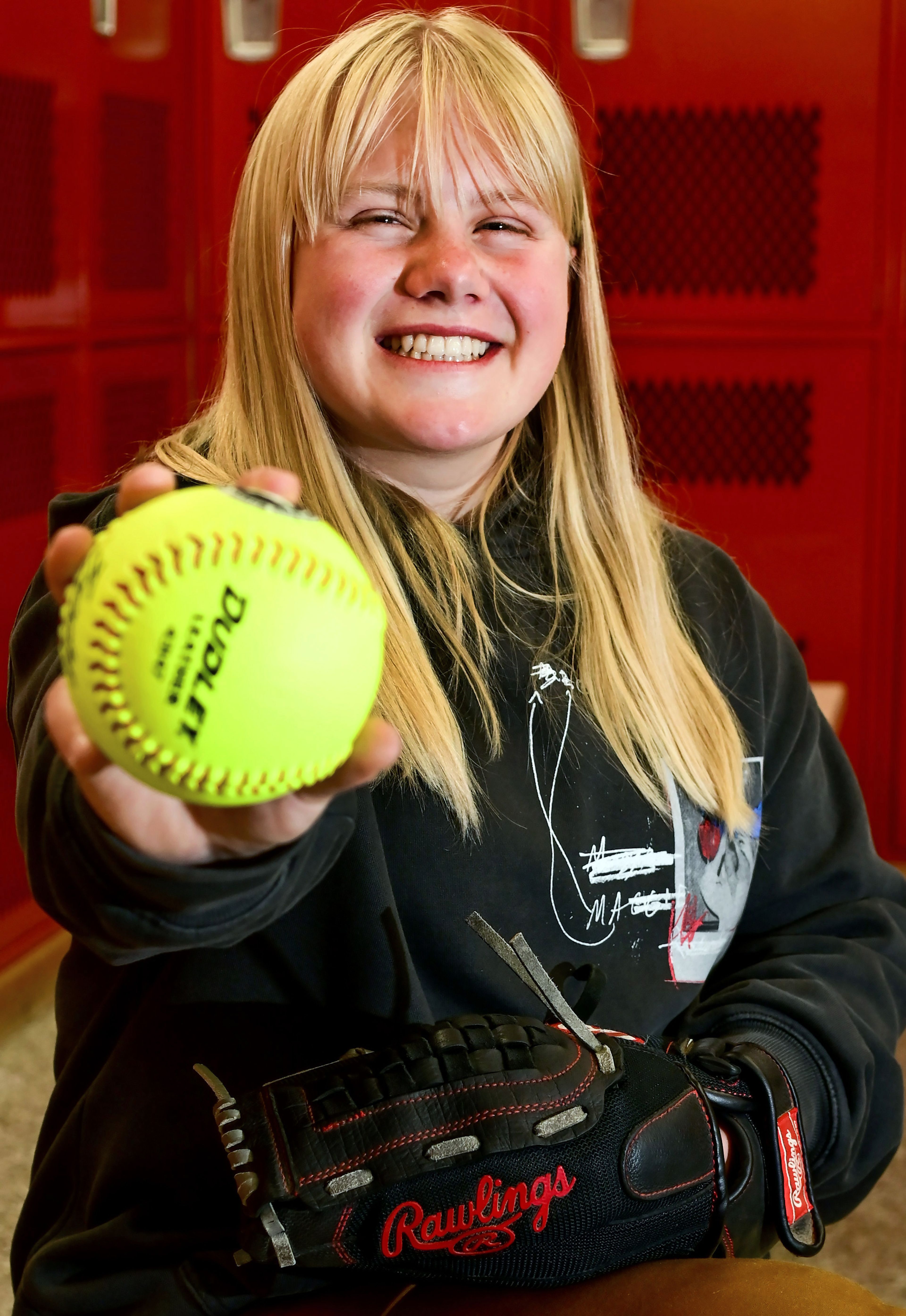 Graduating Moscow High School senior Addison Branen holds out a softball while wearing her glove in the school’s locker room on Tuesday. Branen is a 4.0 student who is signed to play college softball.