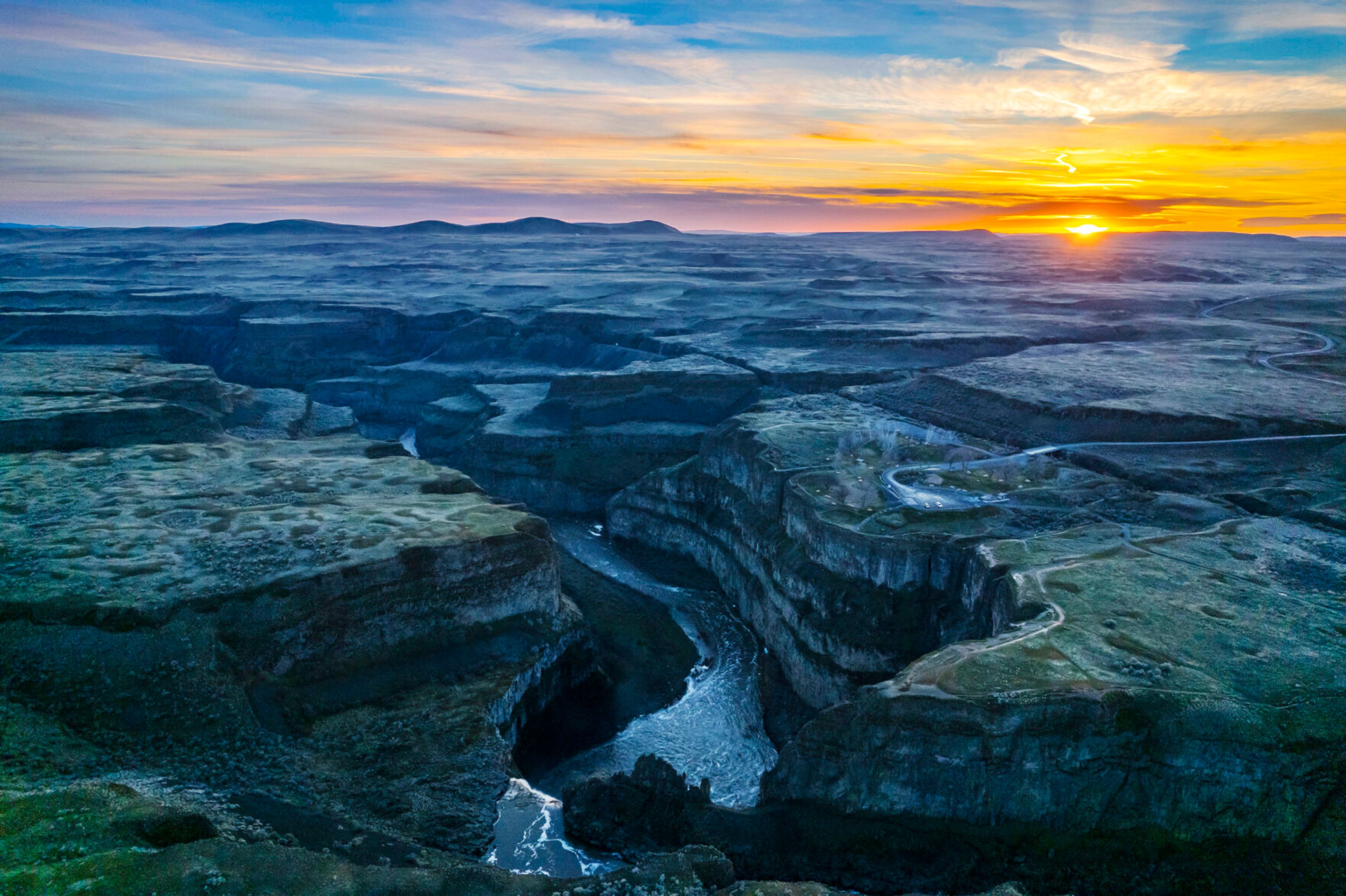 A photo taken with a drone shows the sun setting behind Palouse Falls in early March.