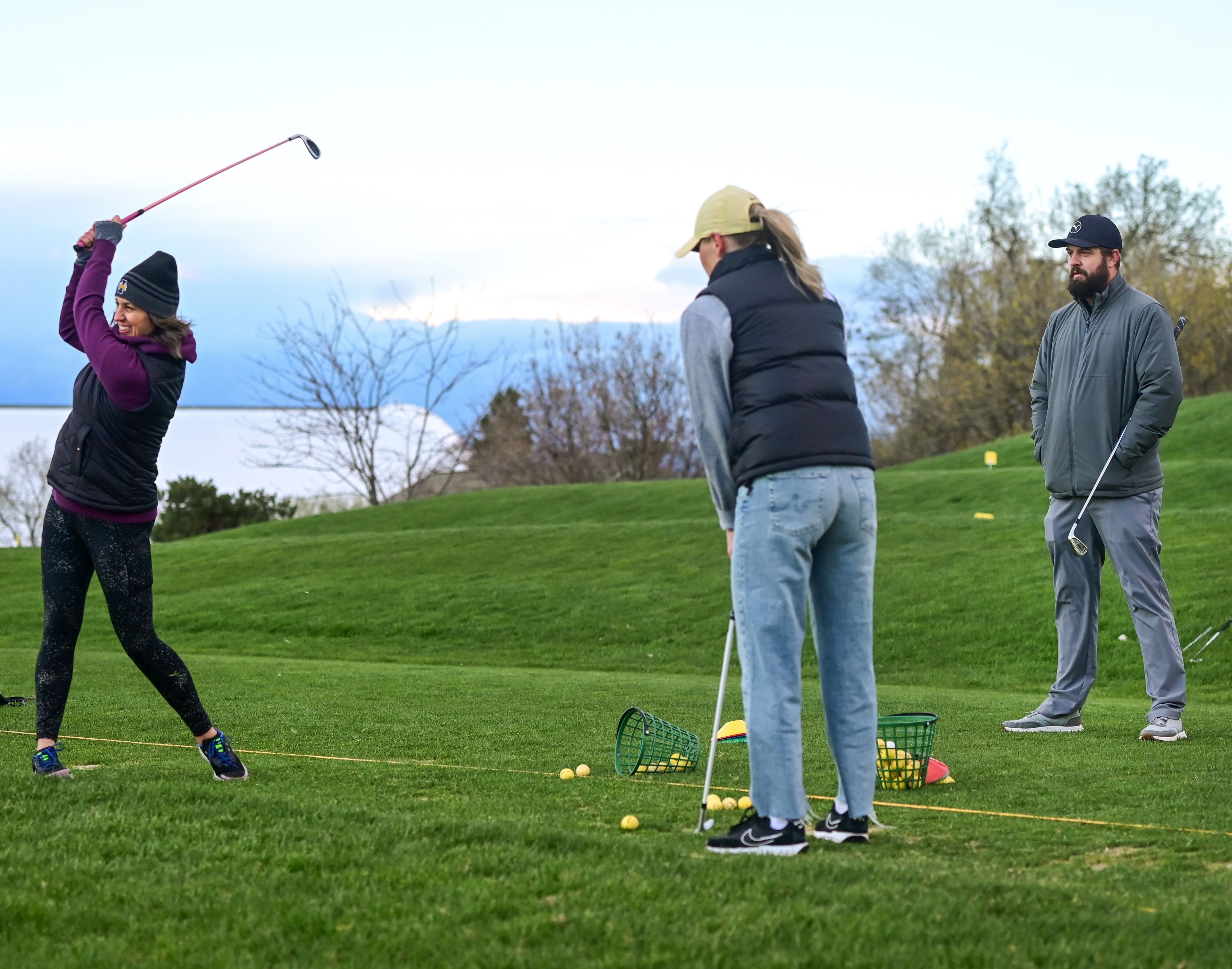 Moscow residents Meghan Raney, left, and Shelly Clark, center, practice a new grip at the driving range under the watch of instructor and head golf professional Michael Wagner, right, during a women’s class at the University of Idaho Golf Course in Moscow on Tuesday.