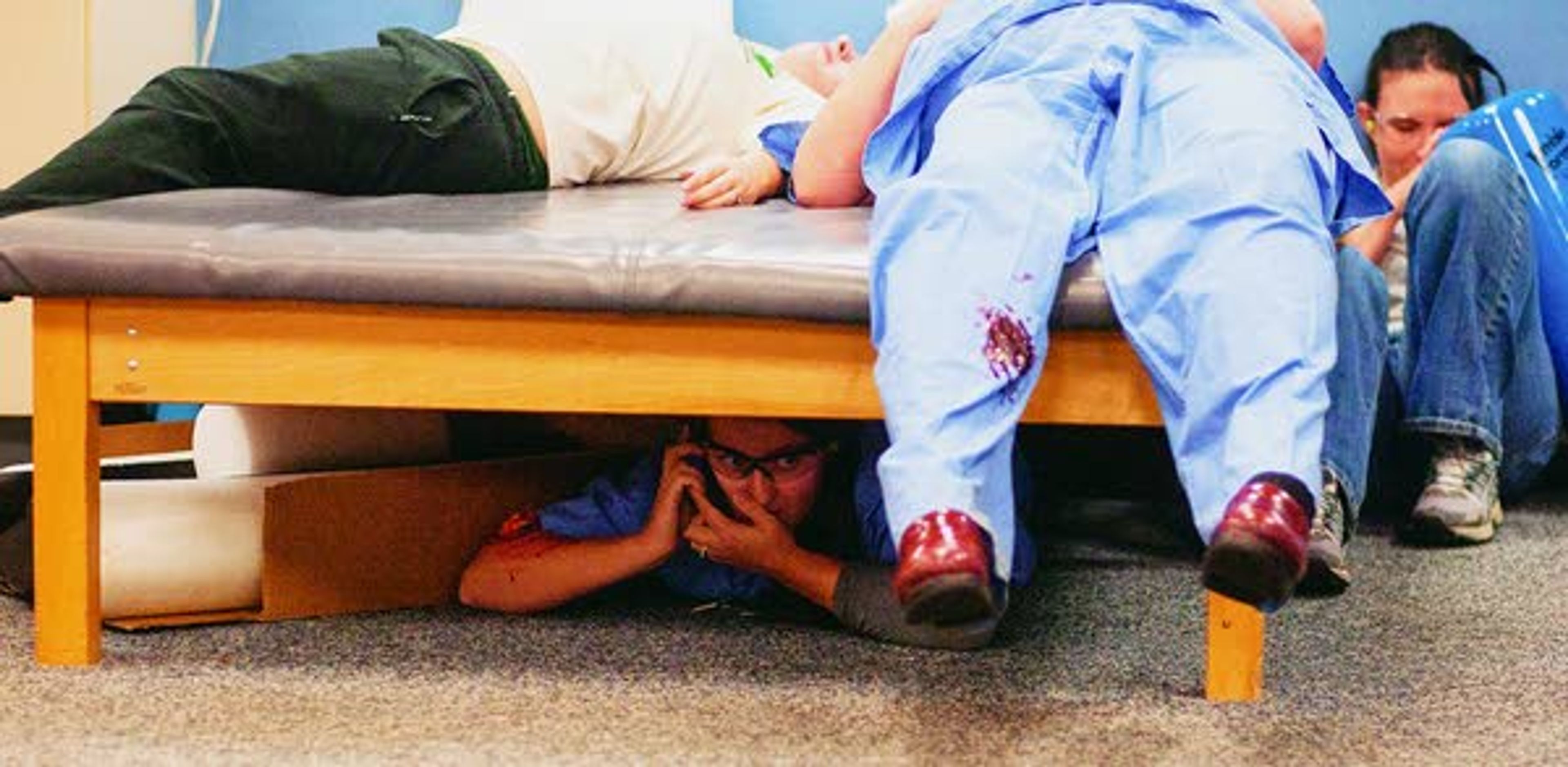 Katie Peet-Walker Bystrom, bottom, calls 911 from under a therapy table during an active shooter response drill run by the Pullman Police Department on Sunday at Summit Therapy in Pullman.