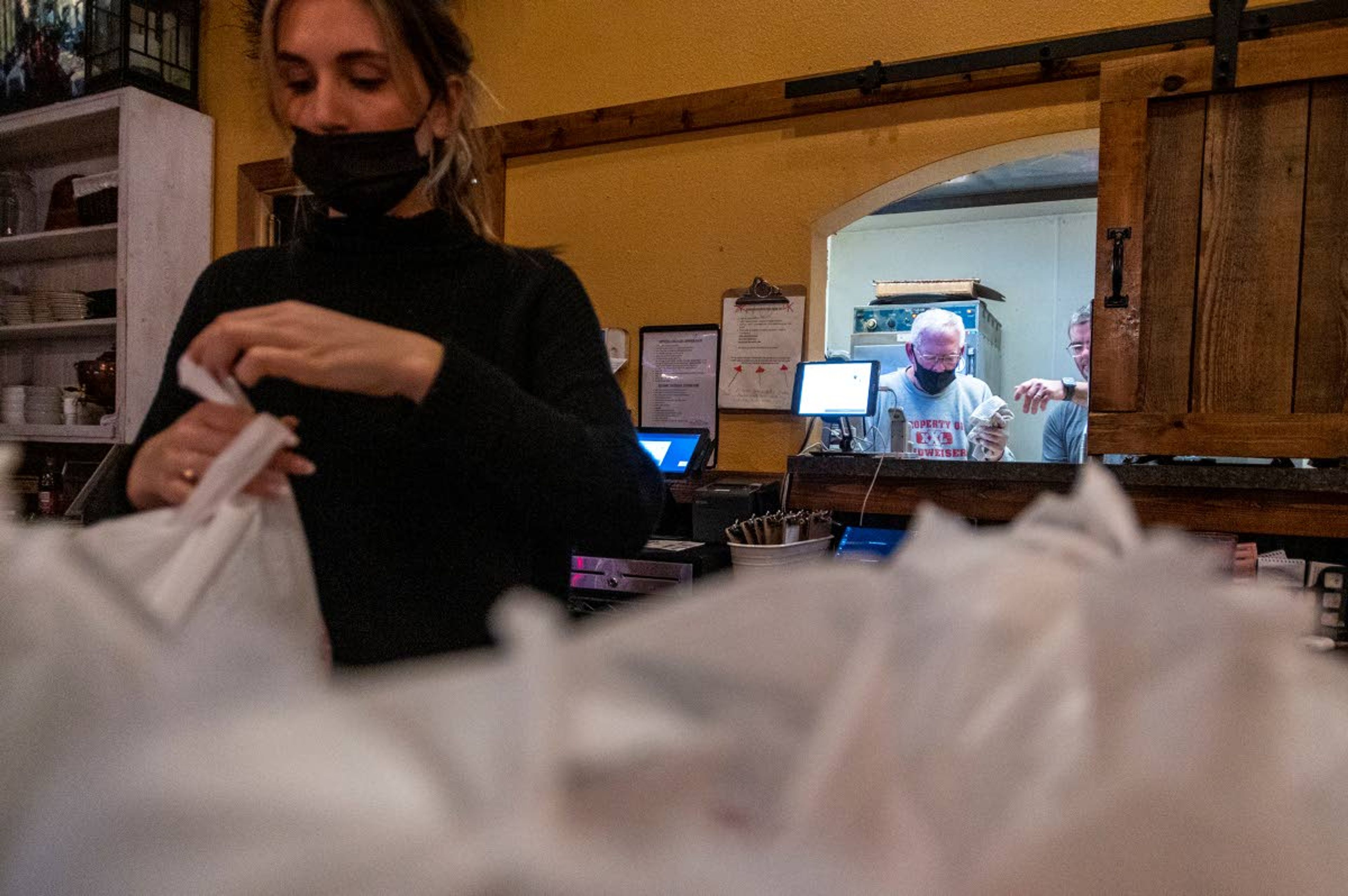 Emma Schimpf, from left, wraps bags while Steve Copeland and Frank Maryott dish meals for the Feeding Our Friends program Tuesday night at Oak on Main in Pullman.