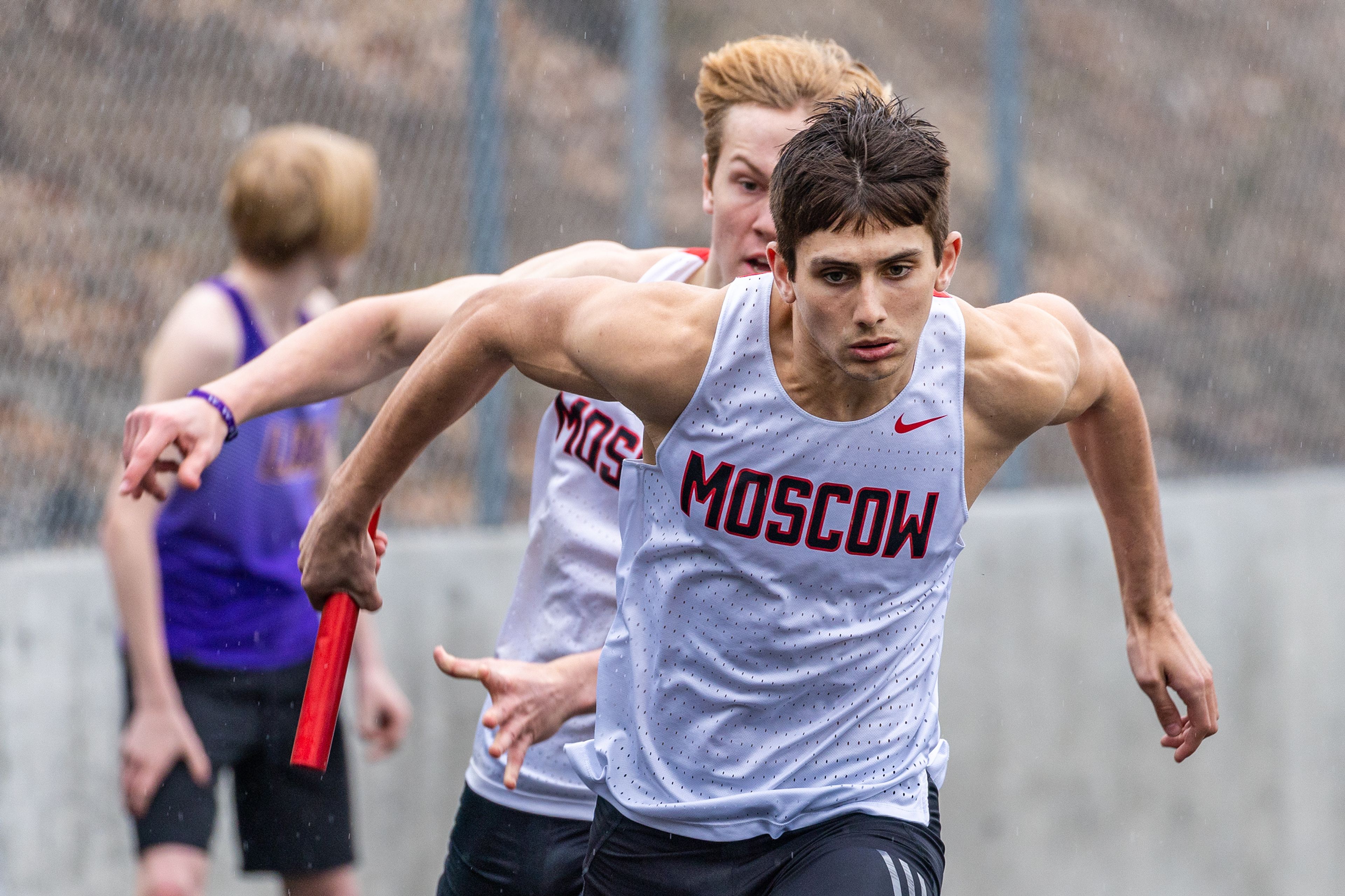 Moscow’s Logan Tate takes the baton from Caleb Skinner in the 4x100 meter relay on April 7 during the Lewiston Open at the Vollmer Bowl in Lewiston.