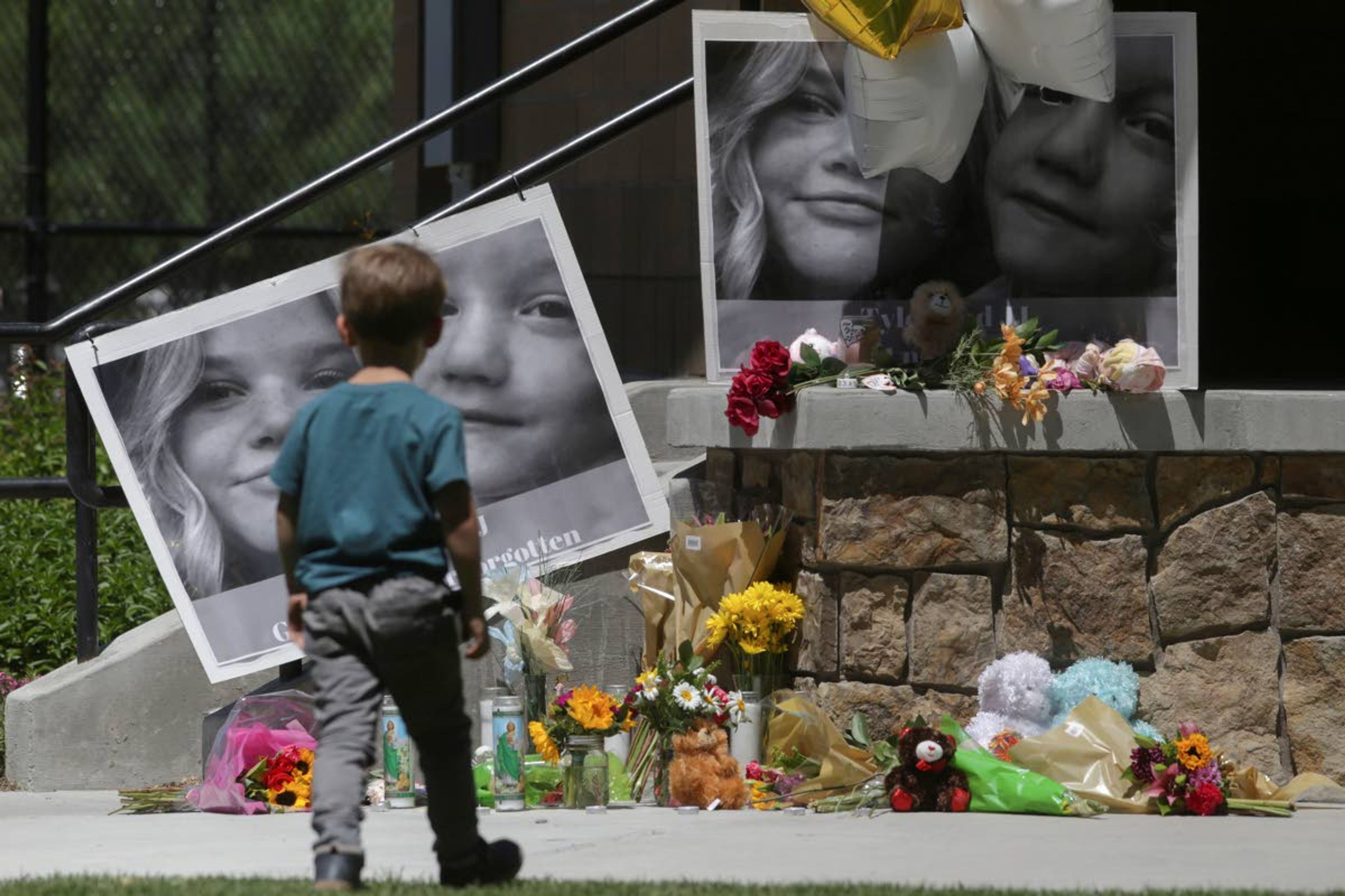 FILE - In this June 11, 2020, file photo, a boy looks at a memorial for Tylee Ryan, 17, and Joshua "JJ" Vallow, 7, at Porter Park in Rexburg, Idaho. Prosecutors say the mother of the two children who were found dead in rural Idaho months after they vanished had conspired with her new husband to hide or destroy the kids’ bodies. The new felony charges against Lori Vallow Daybell came late Monday, June 29. (John Roark/The Idaho Post-Register via AP, File)