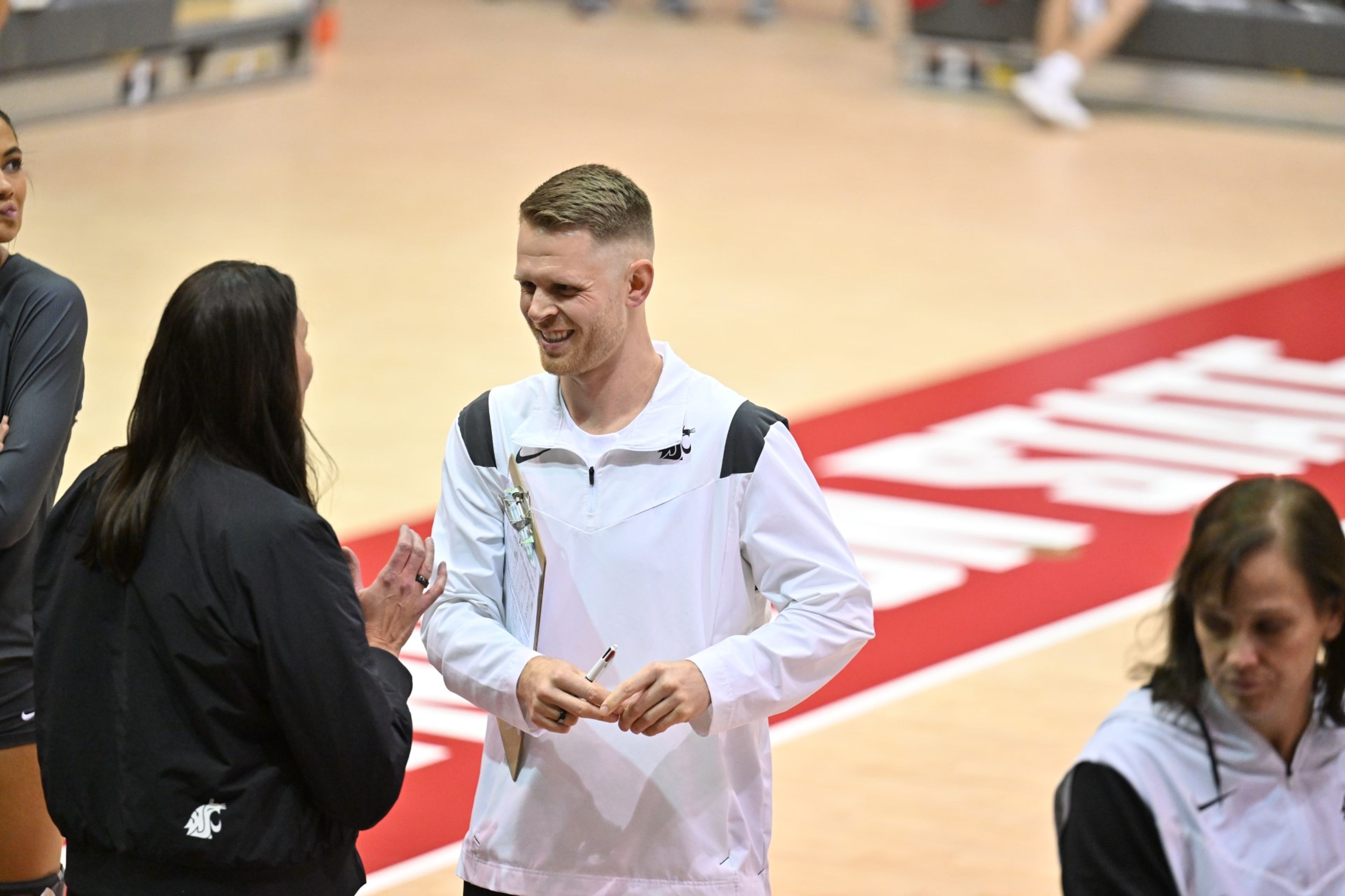 Washington State volleyball coach Korey Schroeder, center, speaks before a match.