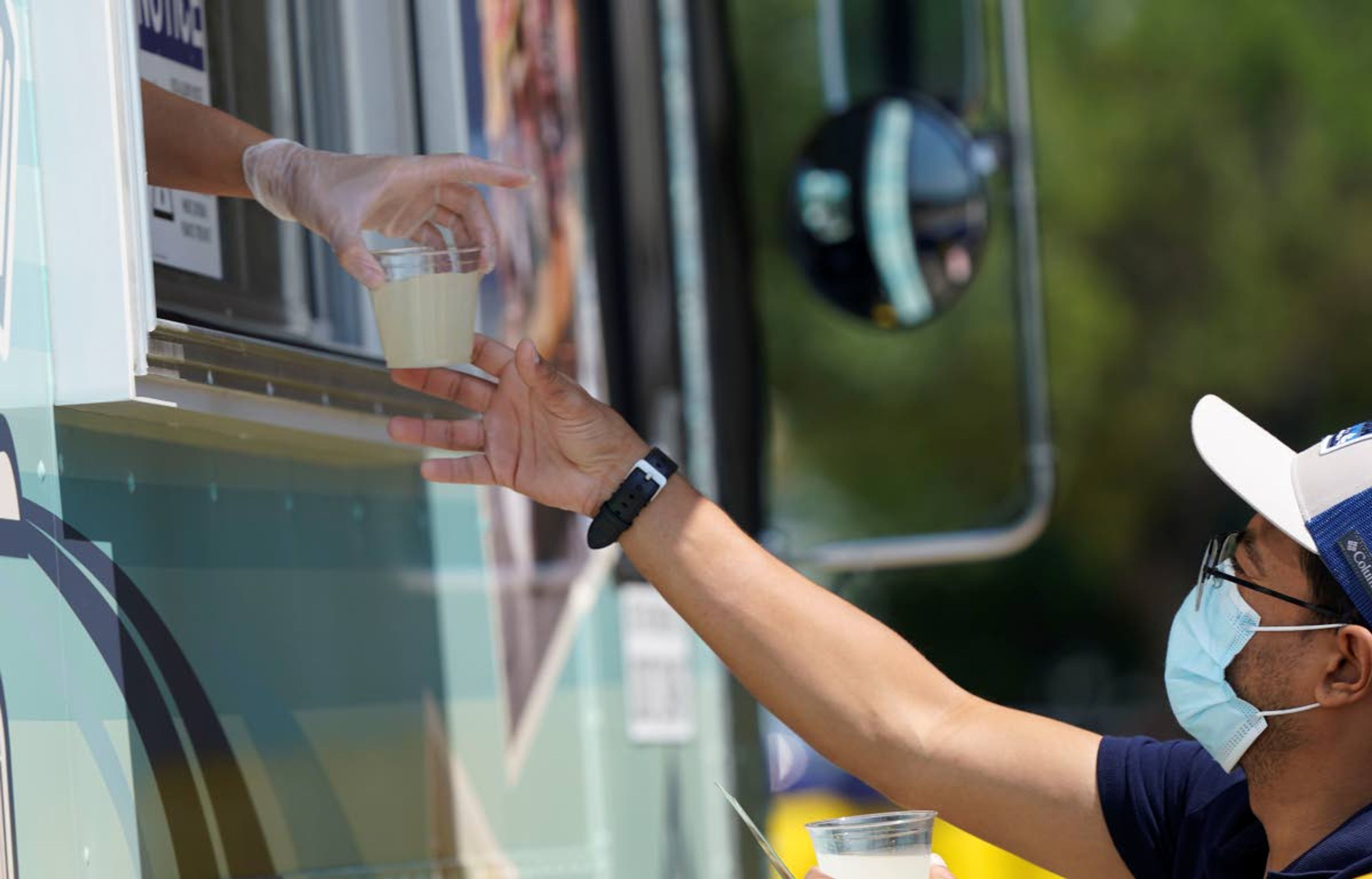 A drink sample is handed to a man outside a food truck window Friday, June 18, 2021, in McKinney, Texas. When the pandemic was declared in March 2020, retailers worried about the potential spread of the coronavirus so they cut off free sampling of everything from food to makeup to toys. But now with vaccinations rolling out and the threat of COVID-19 easing in the U.S., food vendors and stores are feeling confident enough to revive the longstanding tradition. (AP Photo/LM Otero)