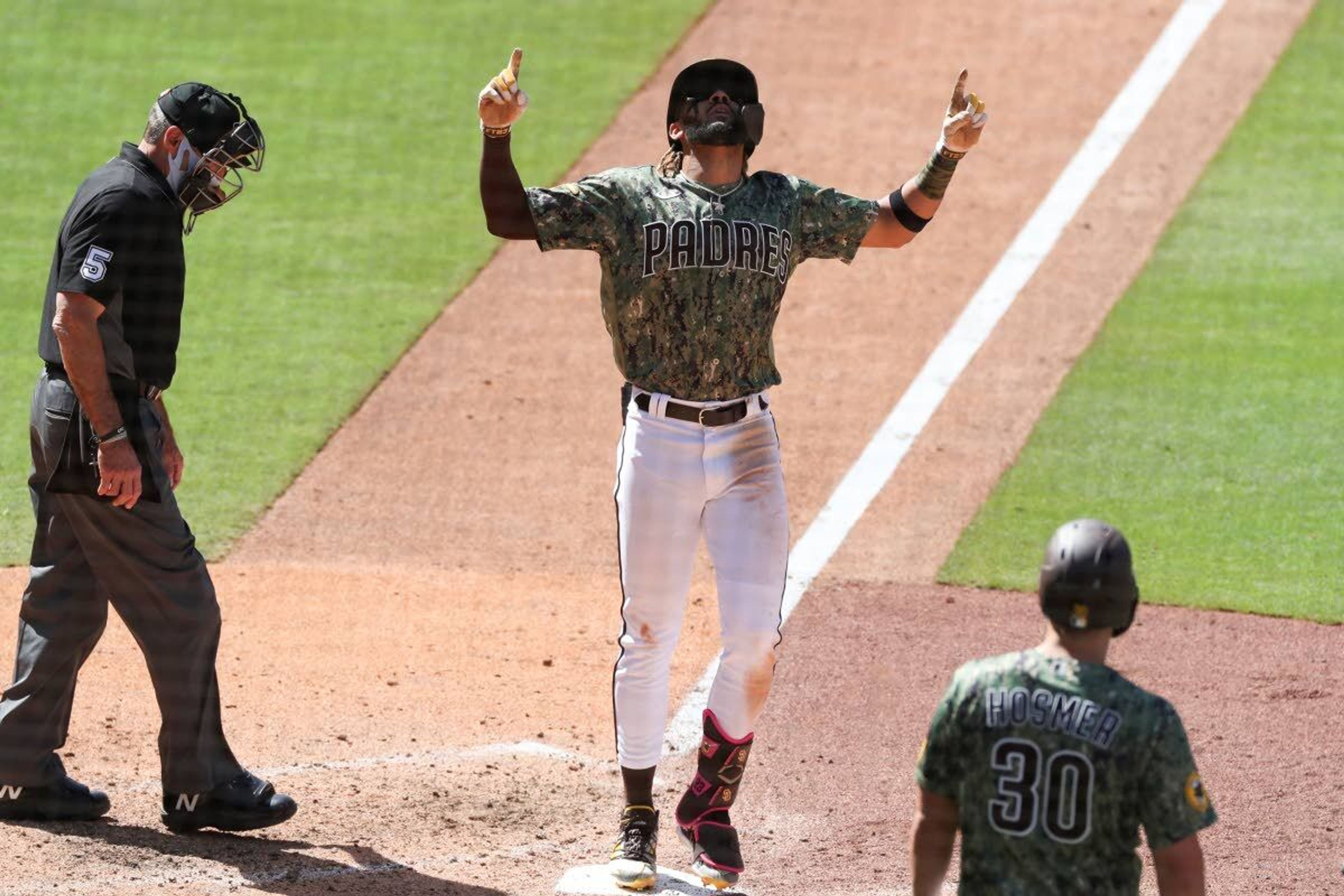 San Diego Padres’ Fernando Tatis Jr., center, points skyward as he crosses home plate after hitting a grand slam off Seattle Mariners relief pitcher Robert Dugger in the seventh inning of a baseball game Sunday, May 23, 2021, in San Diego. (AP Photo/Derrick Tuskan)