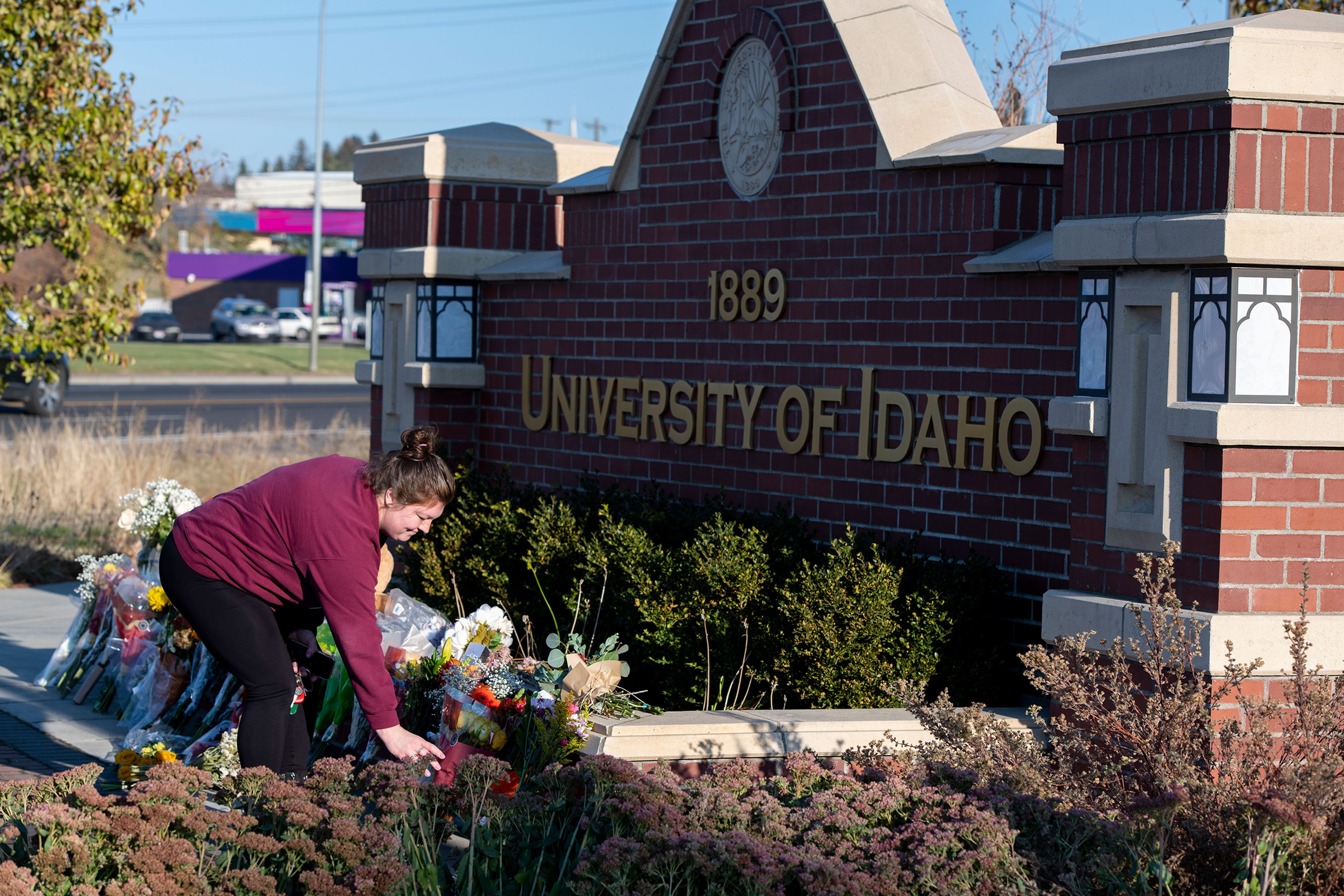 A visitor comes to pay respect Tuesday in honor of four deceased University of Idaho students at a memorial setup along Pullman Road and Perimeter Drive in Moscow.