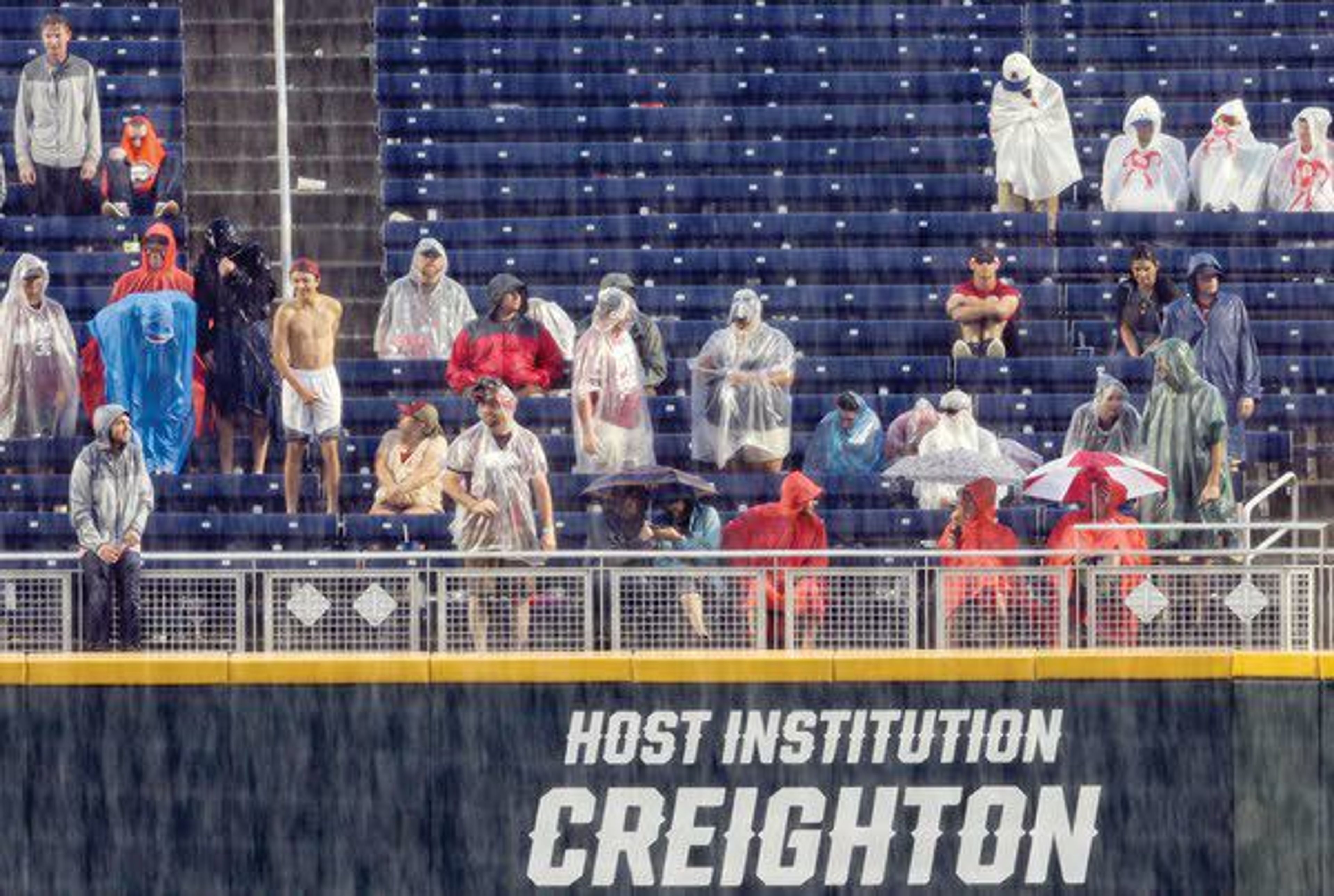 Spectators wait in the rain during a delay Monday before Game 1 of the NCAA College World Series baseball finals between Oregon State and Arkansas in Omaha, Neb.