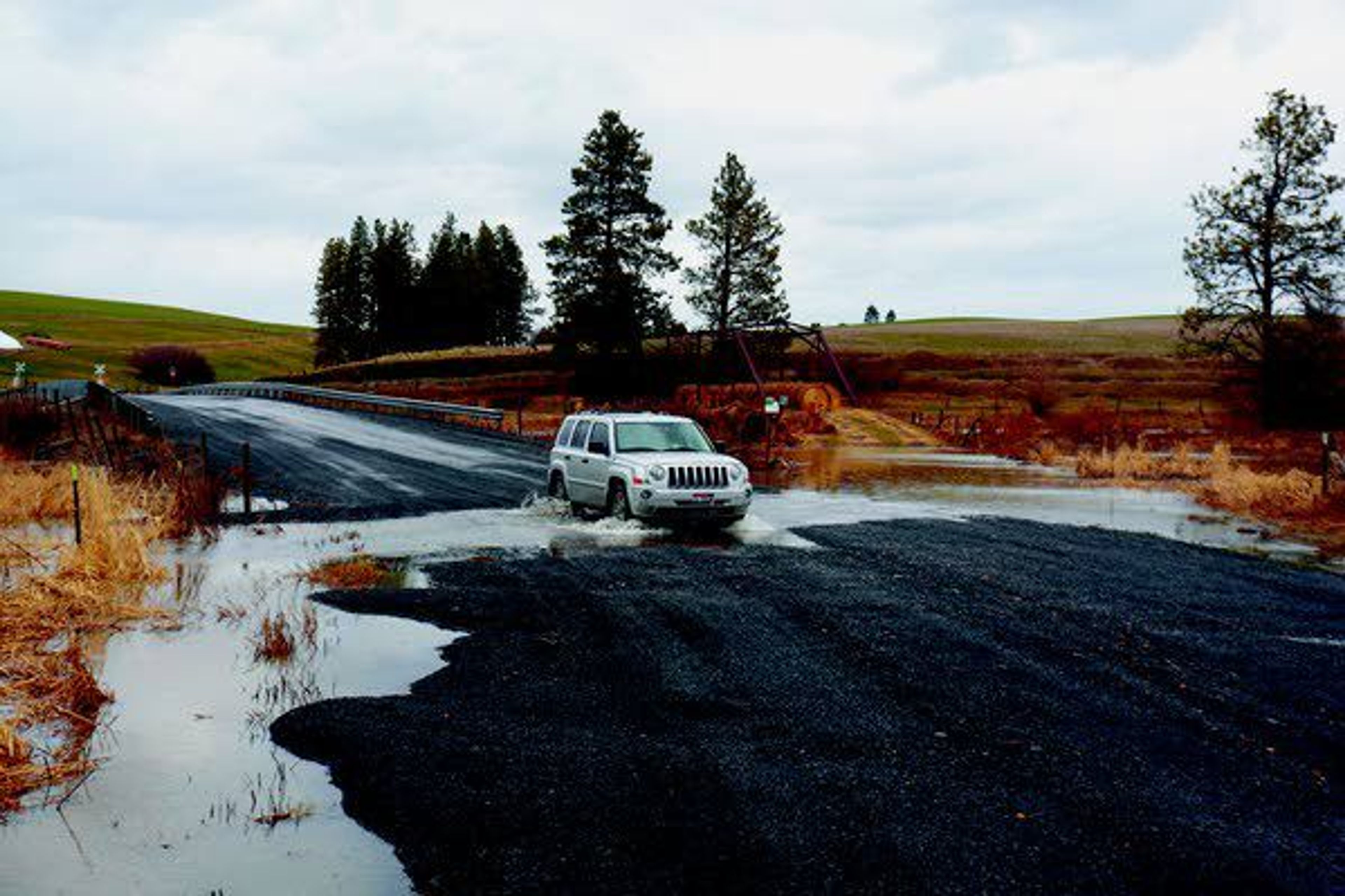 A vehicle crosses a flooded portion of South River Road between Palouse and Potlatch on Tuesday.