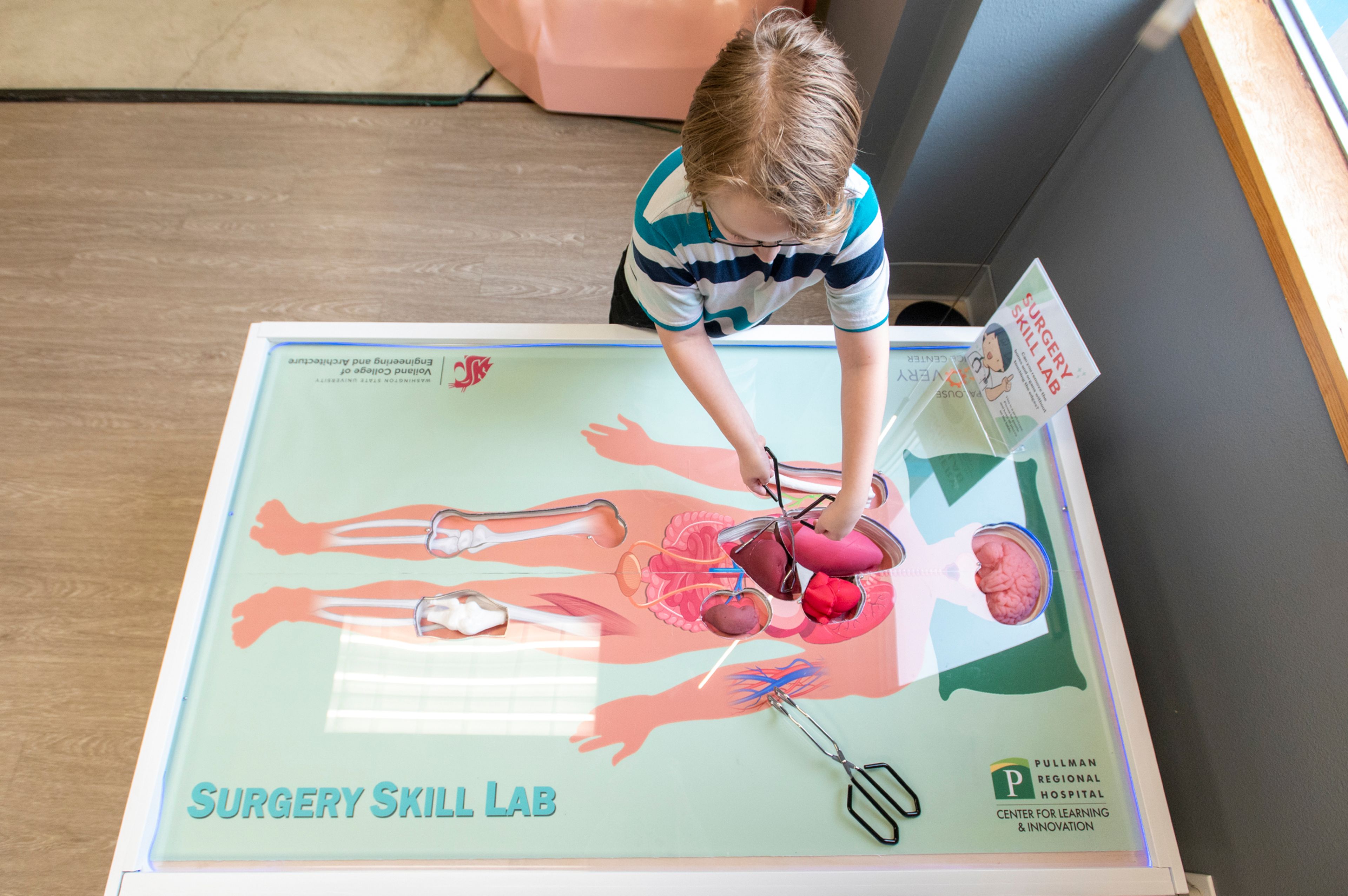 Jason, a fourth grader at Palouse Prairie Charter School, carefully removes organs from a life-sized version of the game Operation at the Palouse Discovery Science Center in Pullman.