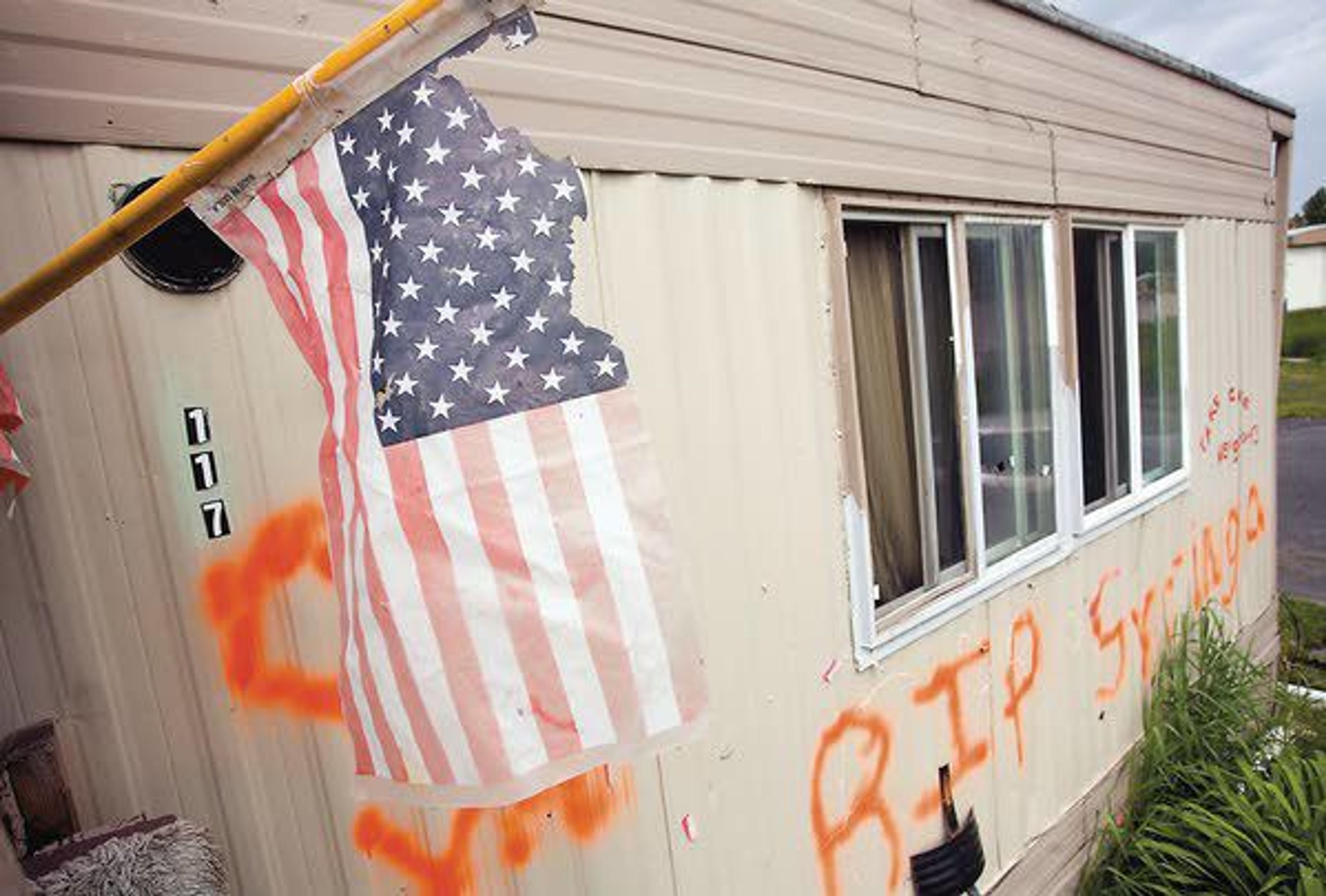 A tattered flag and a spray-painted message are seen outside Cindra Stark’s mobile home on Monday at Syringa Mobile Home Park east of Moscow.