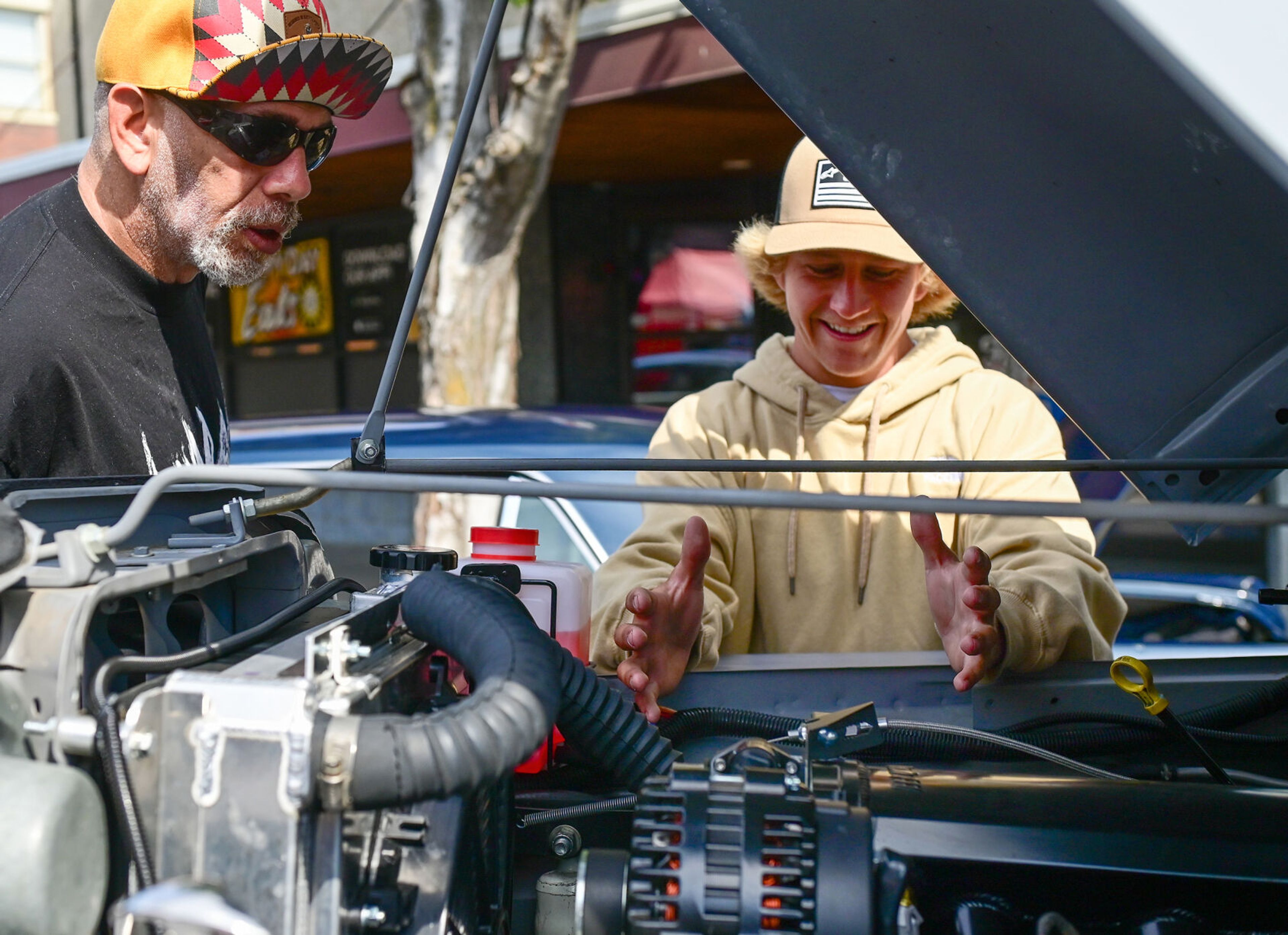 Dylan LaVance, right, shares future plans for under the hood of his 1963 Willys truck with a visitor at the Lewiston Hot August Nights on Saturday along Main Street.