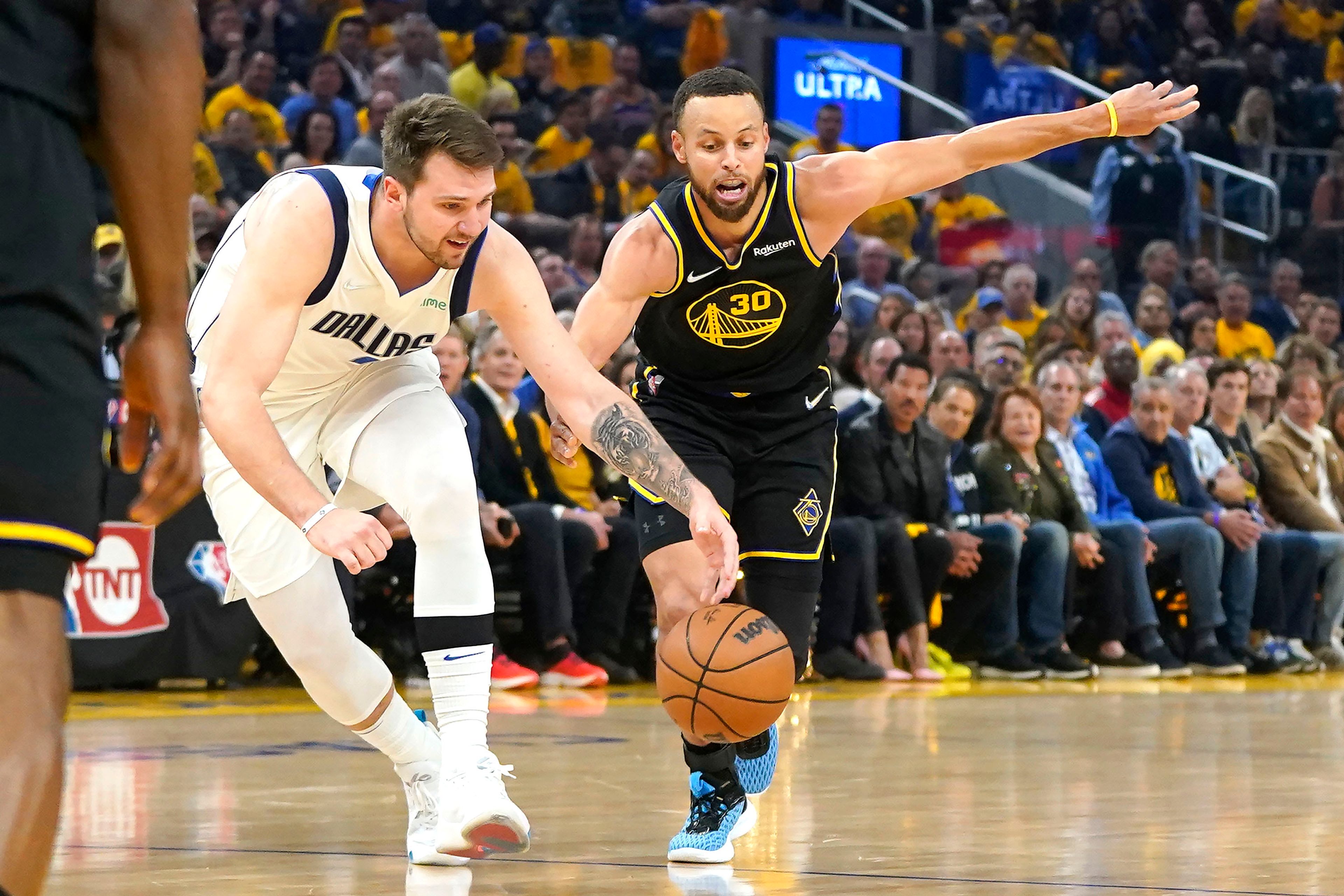 Dallas Mavericks guard Luka Doncic, left, reaches for the ball next to Golden State Warriors guard Stephen Curry (30) during the first half in Game 5 of the NBA basketball playoffs Western Conference finals in San Francisco, Thursday, May 26, 2022. (AP Photo/Jeff Chiu)