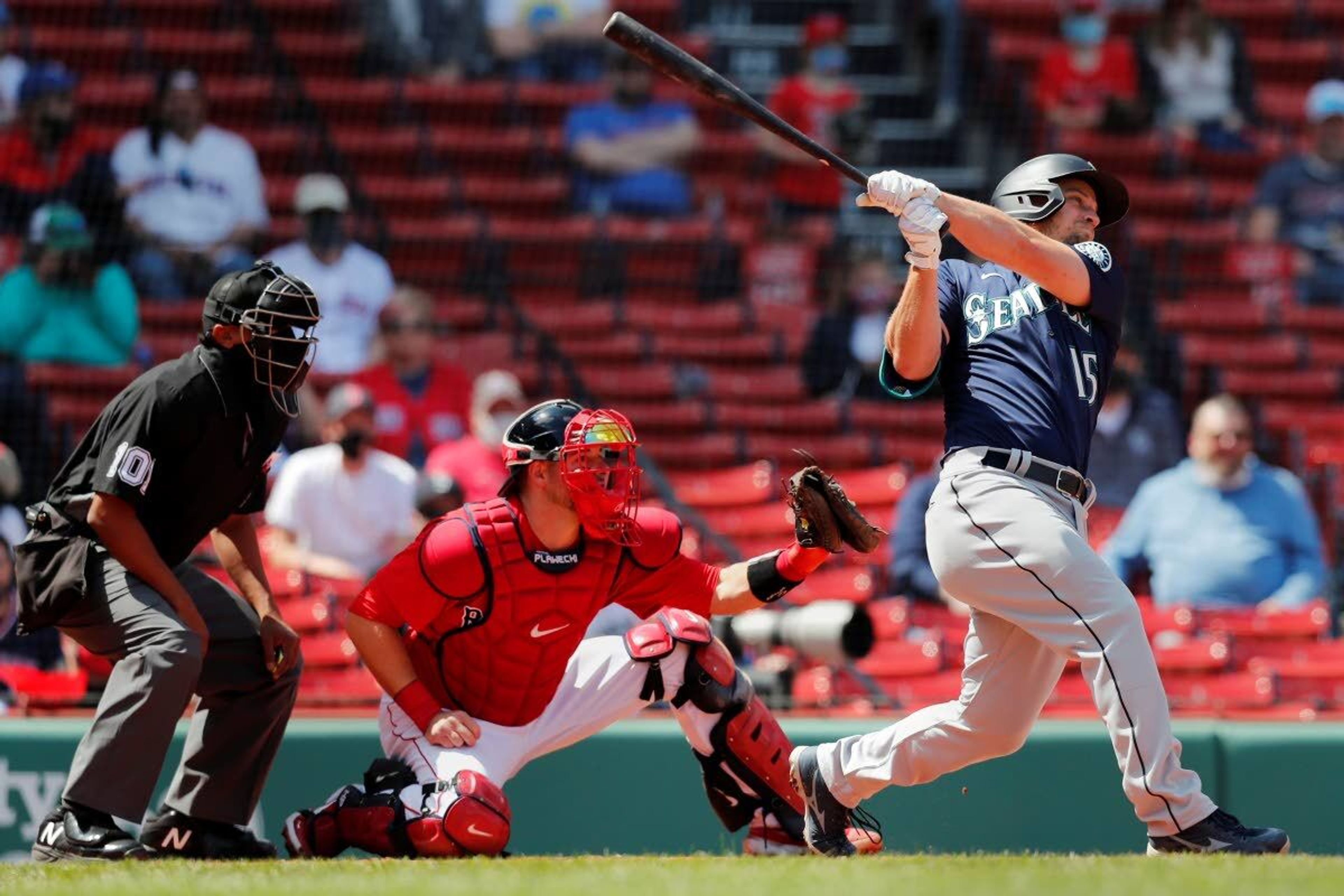 Seattle Mariners' Kyle Seager follows through on his two-run triple in front of Boston Red Sox's Kevin Plawecki during the second inning of a baseball game Saturday, April 24, 2021, in Boston. (AP Photo/Michael Dwyer)