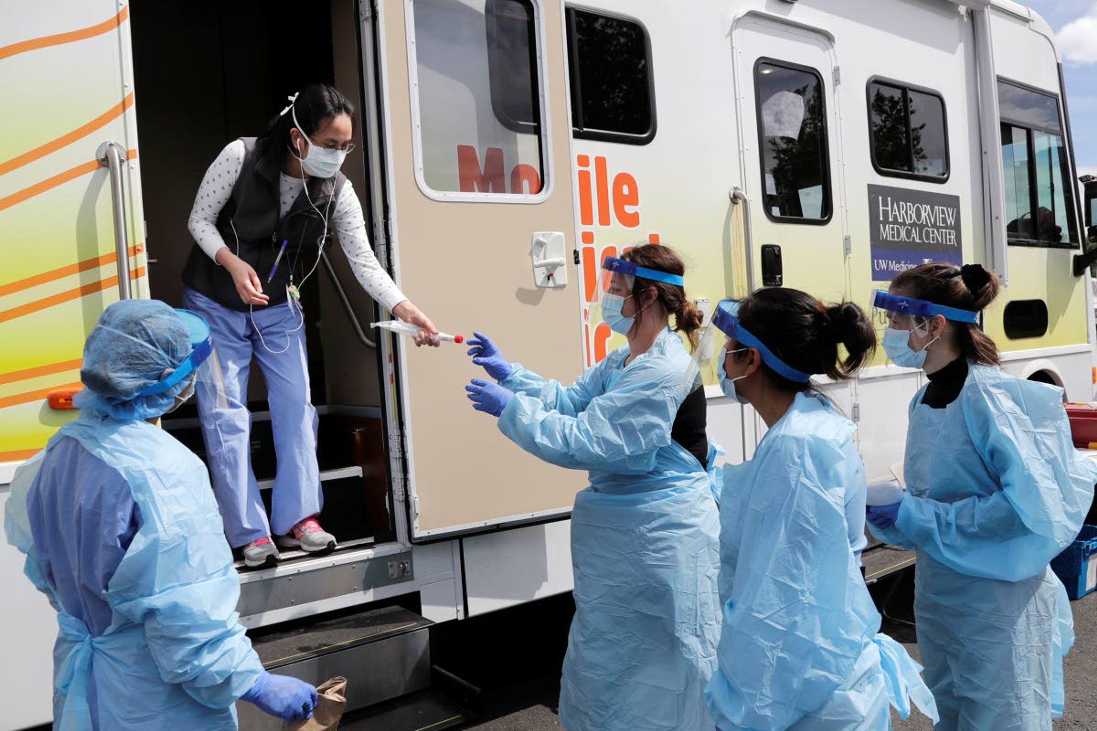 Medical assistants wait to be handed testing kits at a drive-up coronavirus testing site Wednesday, April 29, 2020, in Seattle. The site, open Wednesdays and Saturdays from 10 a.m. to 3 p.m. in the Rainier Beach neighborhood, is available to anyone displaying the virus symptoms, are pregnant, over 60 or have a chronic condition, as well as health care workers and first responders. (AP Photo/Elaine Thompson)