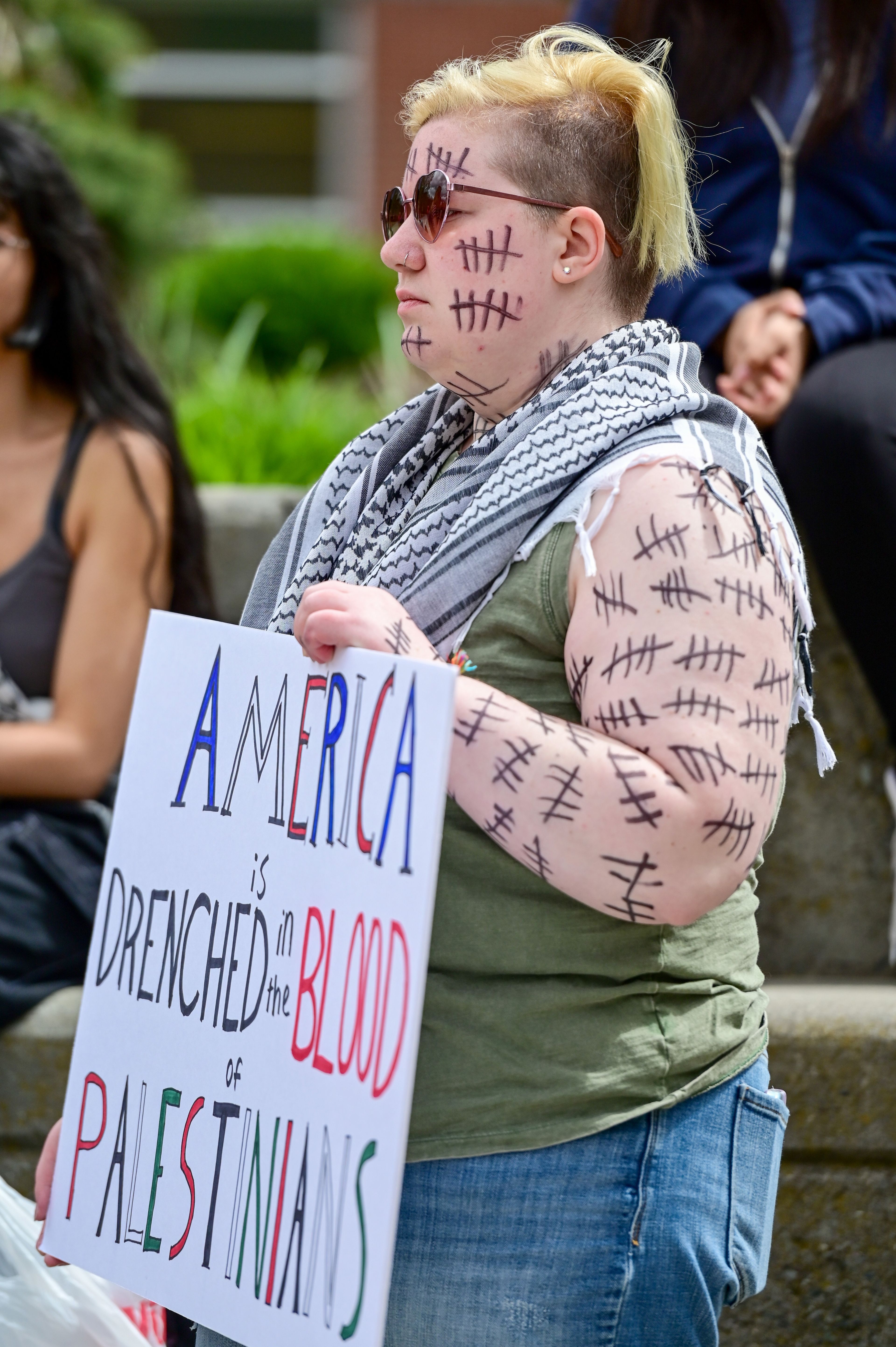 Tallies cover the arms and face of Zeph, a student at the University of Idaho, who spoke to the crowd gathered for a Palestine Week of Action demonstration in Moscow on Thursday. Each tally represents 20 Palestinian children lost in attacks on Gaza, Zeph said.