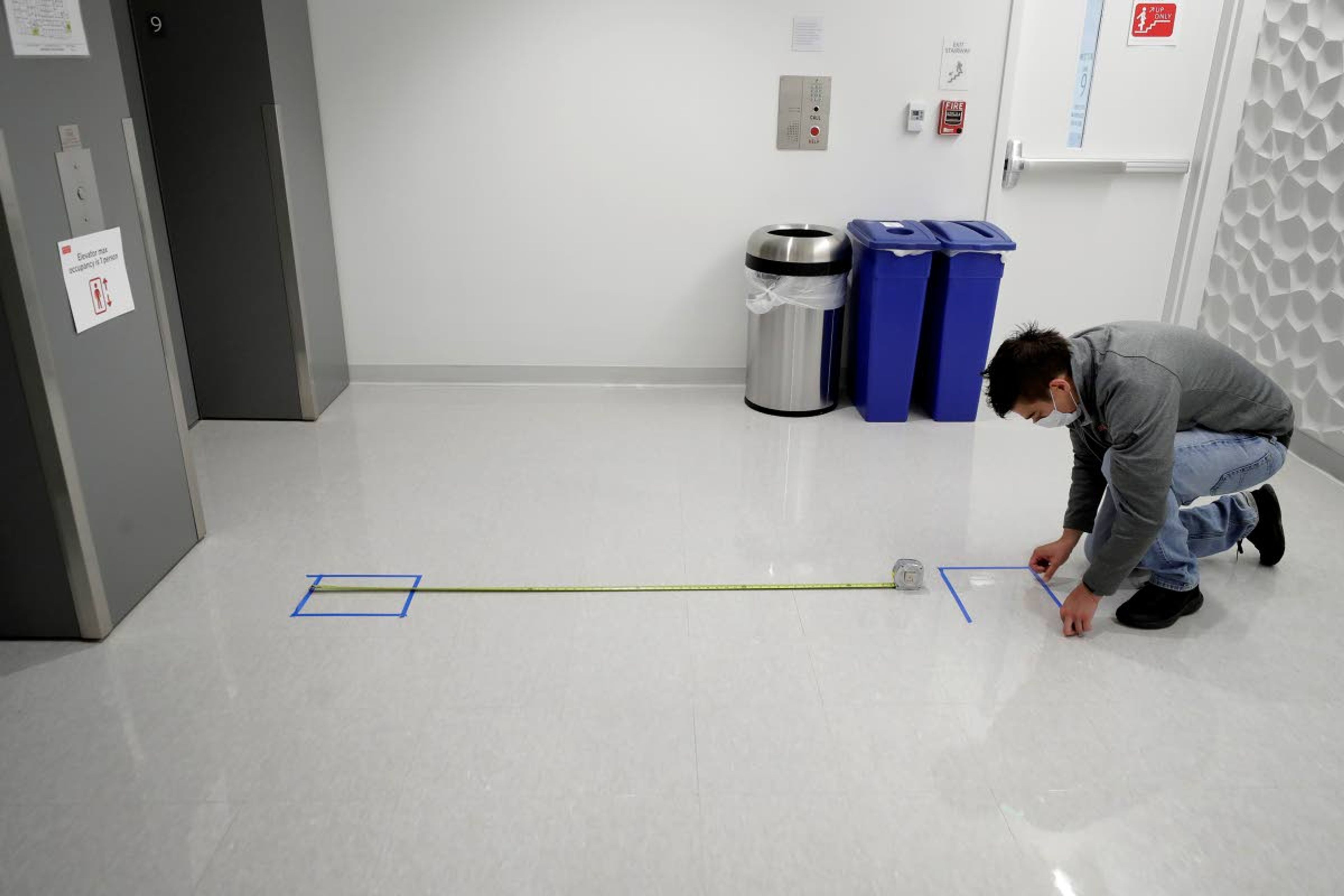 Kevin Gonzales, director of operations at the Rajen Kilachand Center for Integrated Life Sciences and Engineering, at Boston University, places safe distancing floor markings near an elevator on the school’s campus in Boston on Thursday.