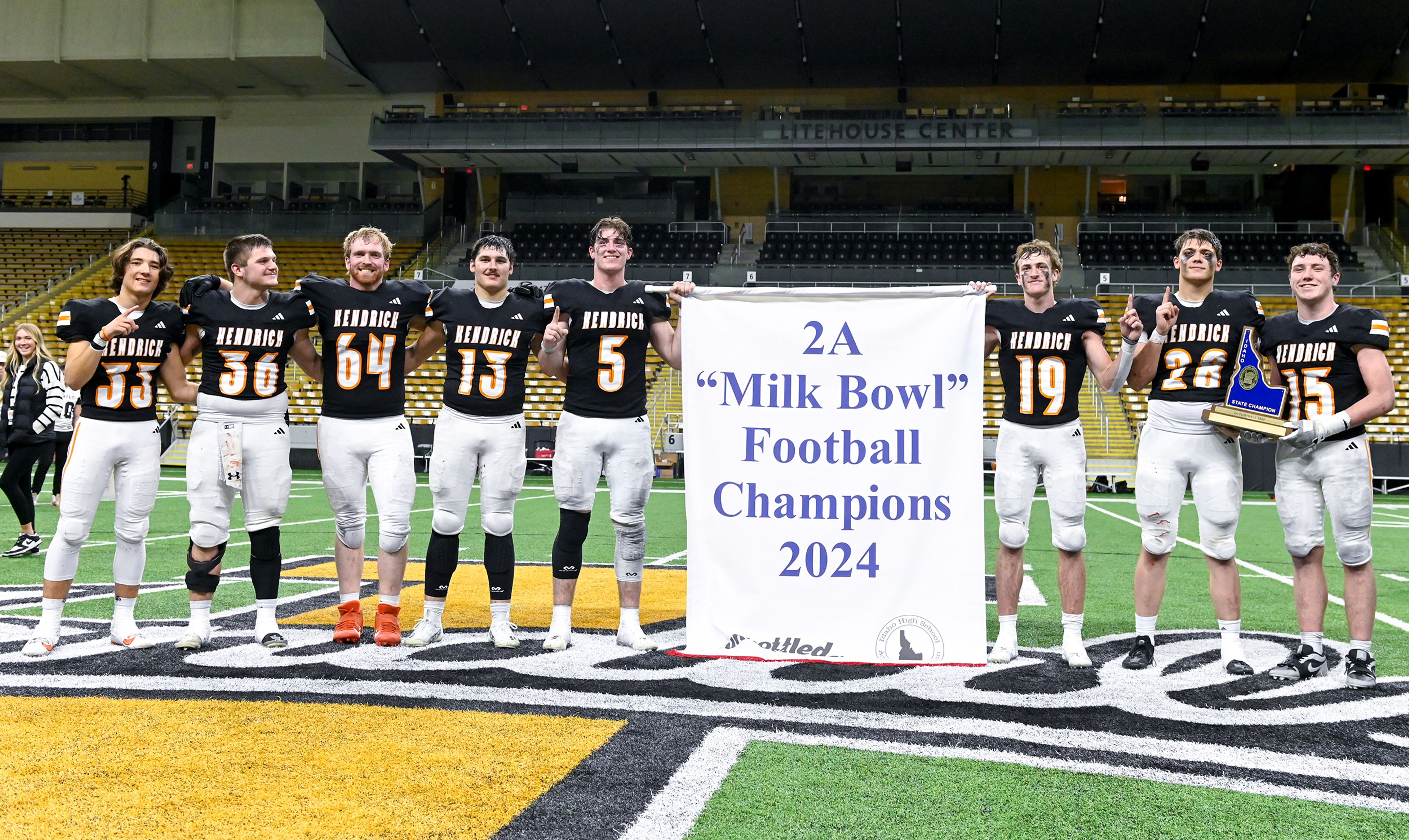 Kendrick seniors pose with a trophy and banner celebrating their Idaho Class 2A state championship win over Butte County at the P1FCU Kibbie Dome in Moscow.