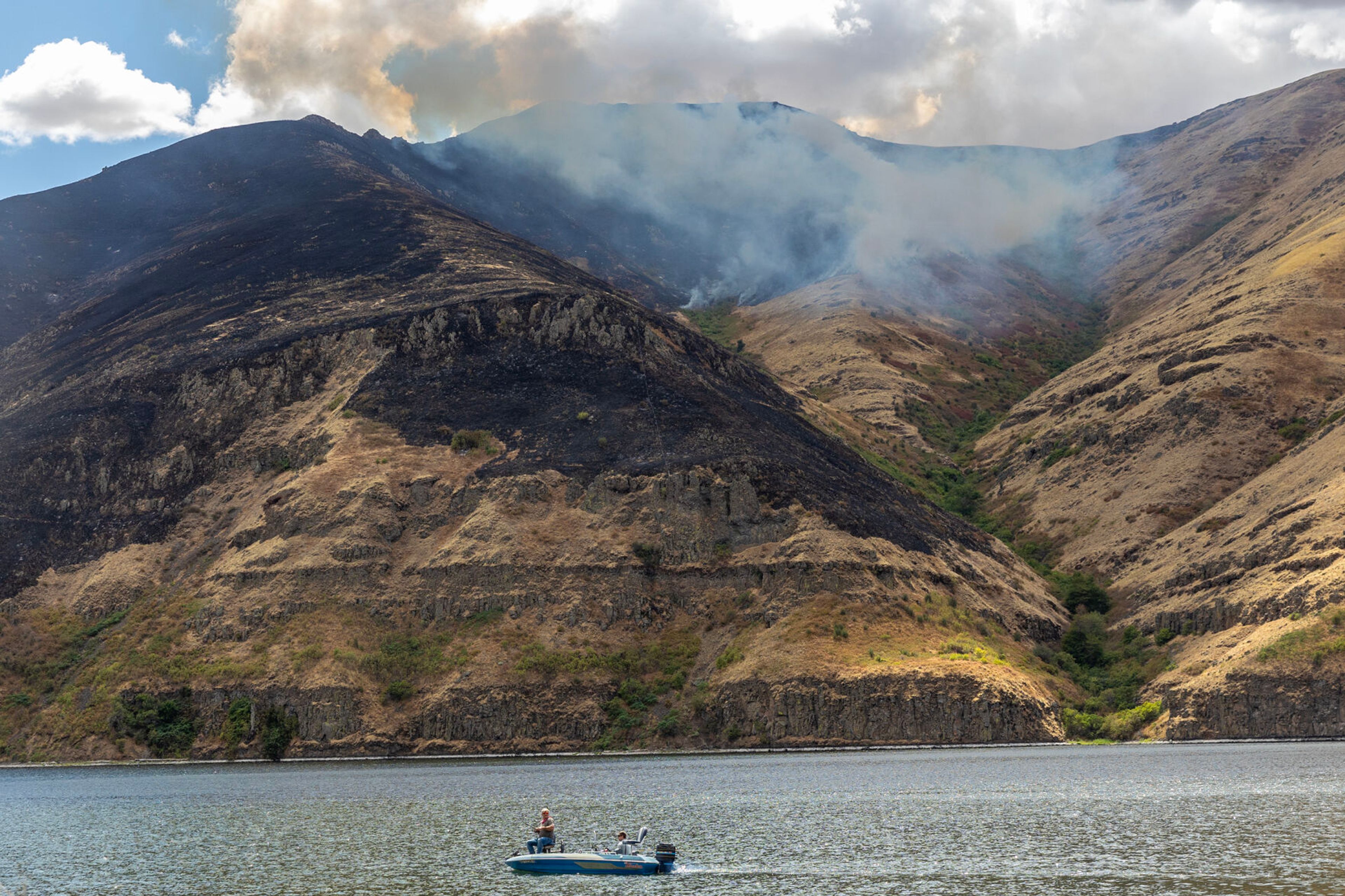 A boat moves on the Snake River as the Lower Granite Fire burns on the hillsides Tuesday off the Snake River.