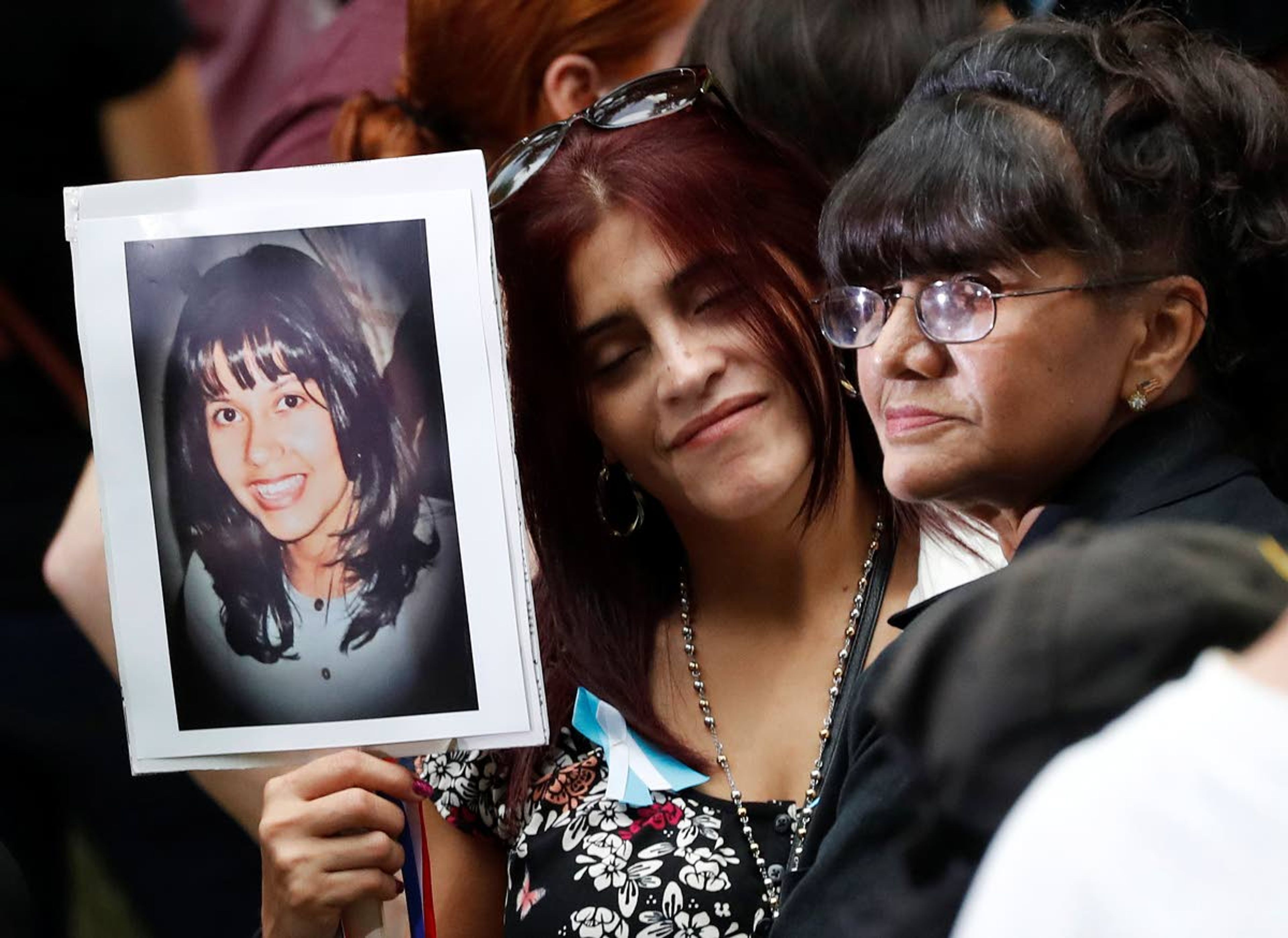 In this Sept. 11, 2016, file photo, mourners hold a photo of their loved one during the 15th anniversary of the attacks of the World Trade Center at the National September 11 Memorial in New York. The coronavirus pandemic has reshaped how the U.S. is observing the anniversary of 9/11. The terror attacks' 19th anniversary will be marked Friday, Sept. 11, 2020, by dueling ceremonies at the Sept. 11 memorial plaza and a corner nearby in New York.