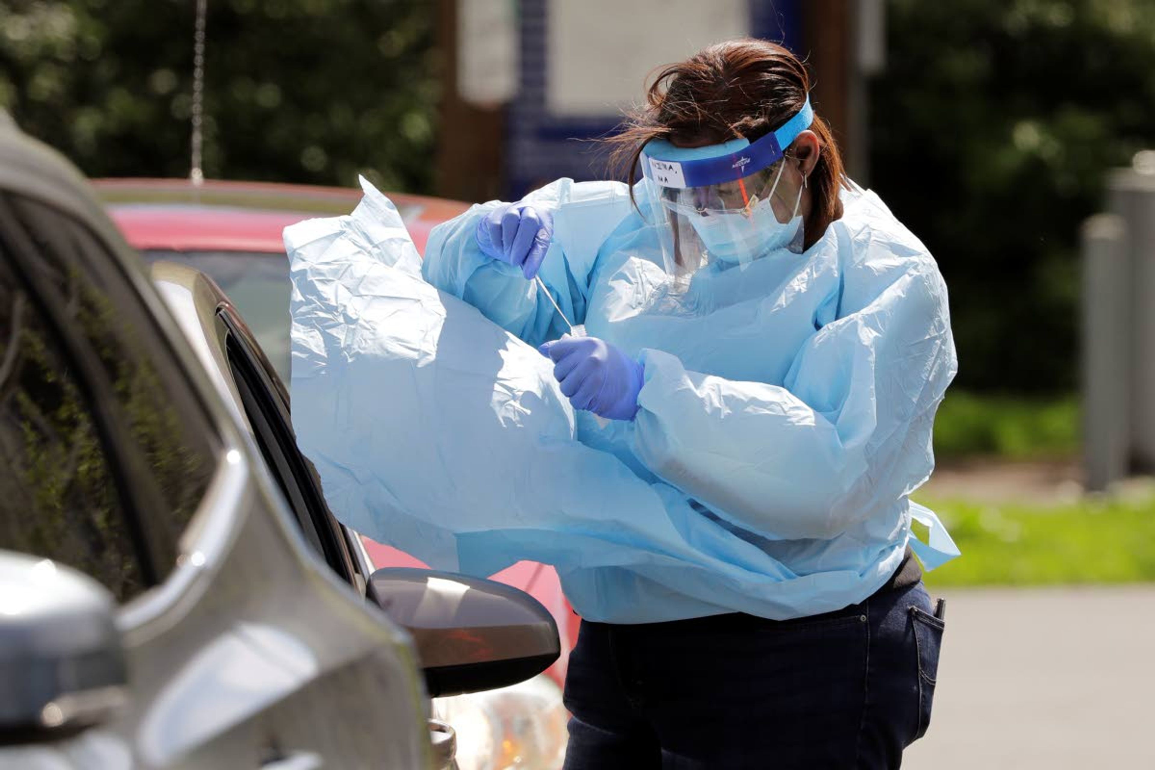 The protective gown of medical assistant Nina Daniels billows in the wind as she puts away a swab she took from a driver at a drive-up coronavirus testing site Wednesday, April 29, 2020, in Seattle. The site, open Wednesdays and Saturdays from 10 a.m. to 3 p.m. in the Rainier Beach neighborhood, is available to anyone displaying the virus symptoms, are pregnant, over 60 or have a chronic condition, as well as health care workers and first responders. (AP Photo/Elaine Thompson)