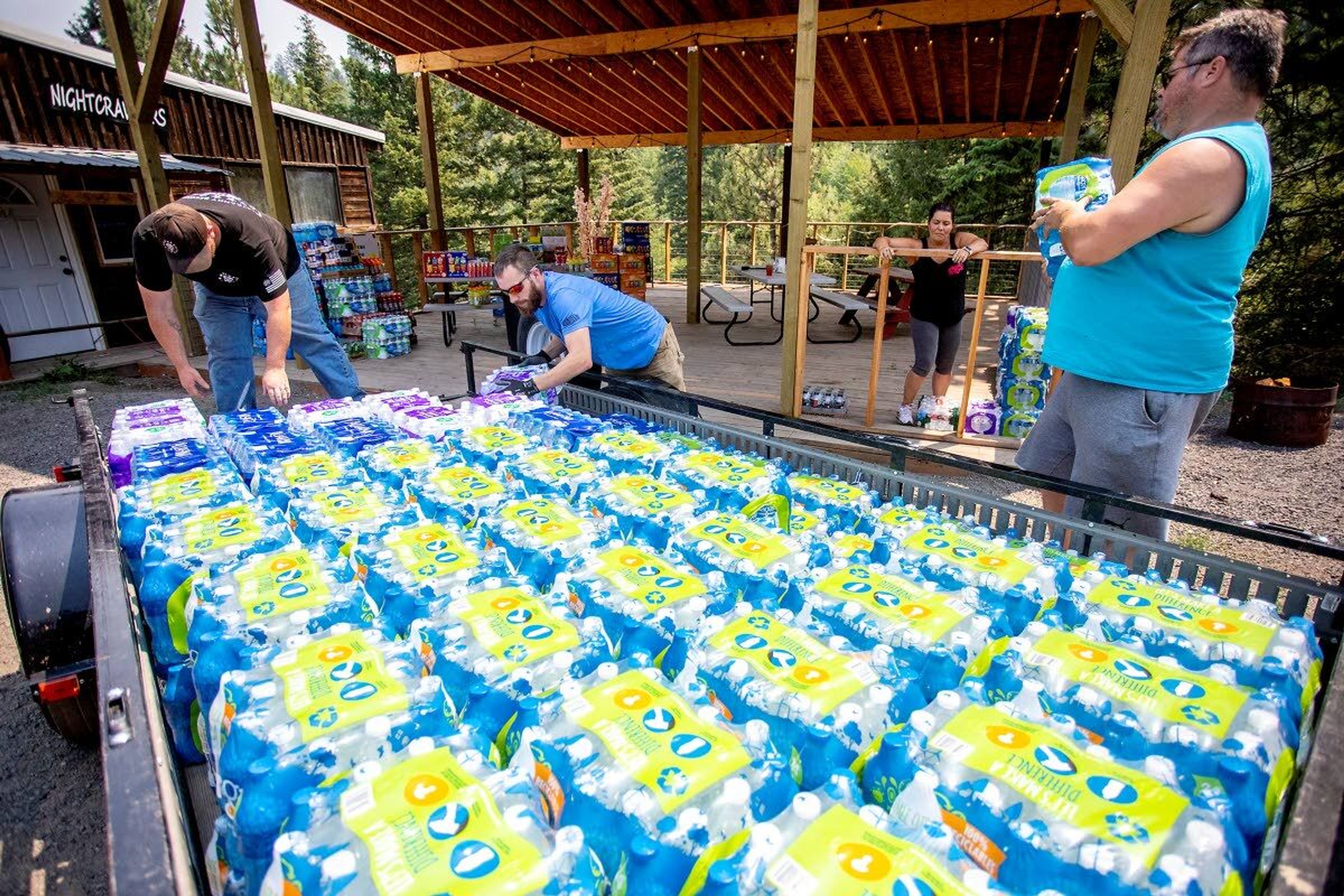 Volunteers unload a trailer full of water at the Waha Bar and Grill on Saturday.