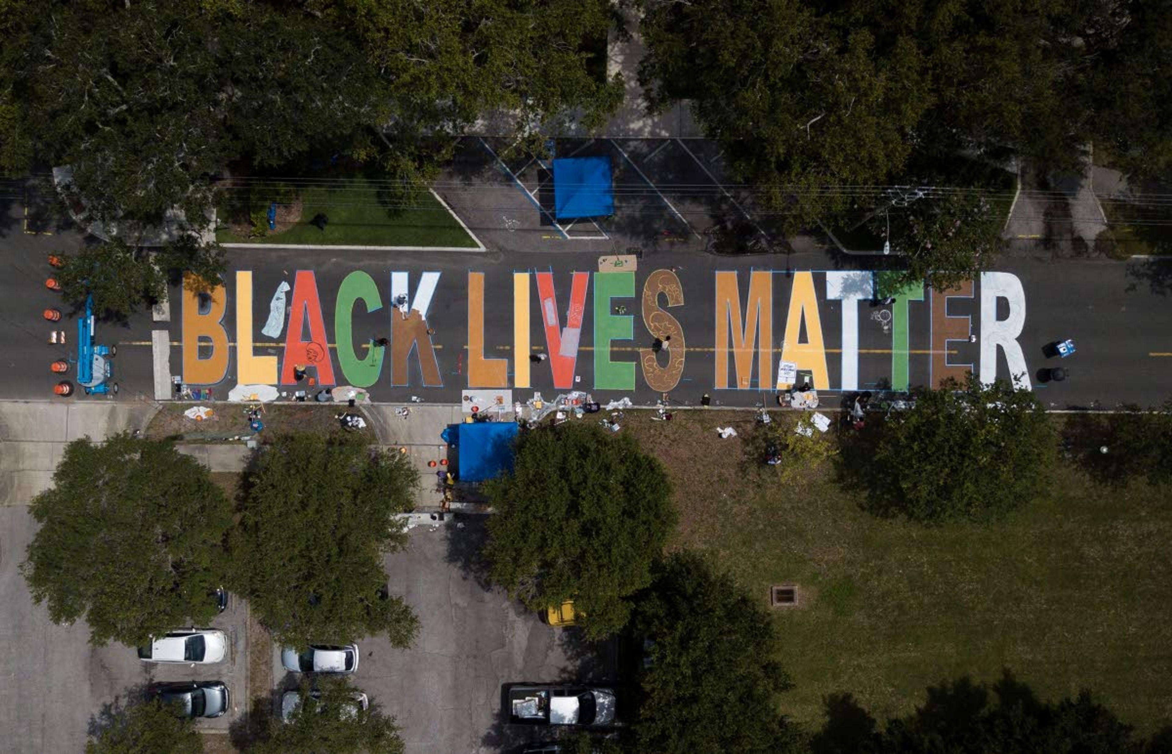 Local artists collaborate on painting a Black Lives Matter street mural in front of the Dr. Carter G. Woodson African American Museum, in St. Petersburg on Thursday, June 18, 2020. The mural will be ready when the city of St Pete kicks of its Juneteenth celebrations on Friday morning. (Dirk Shadd/Tampa Bay Times via AP)