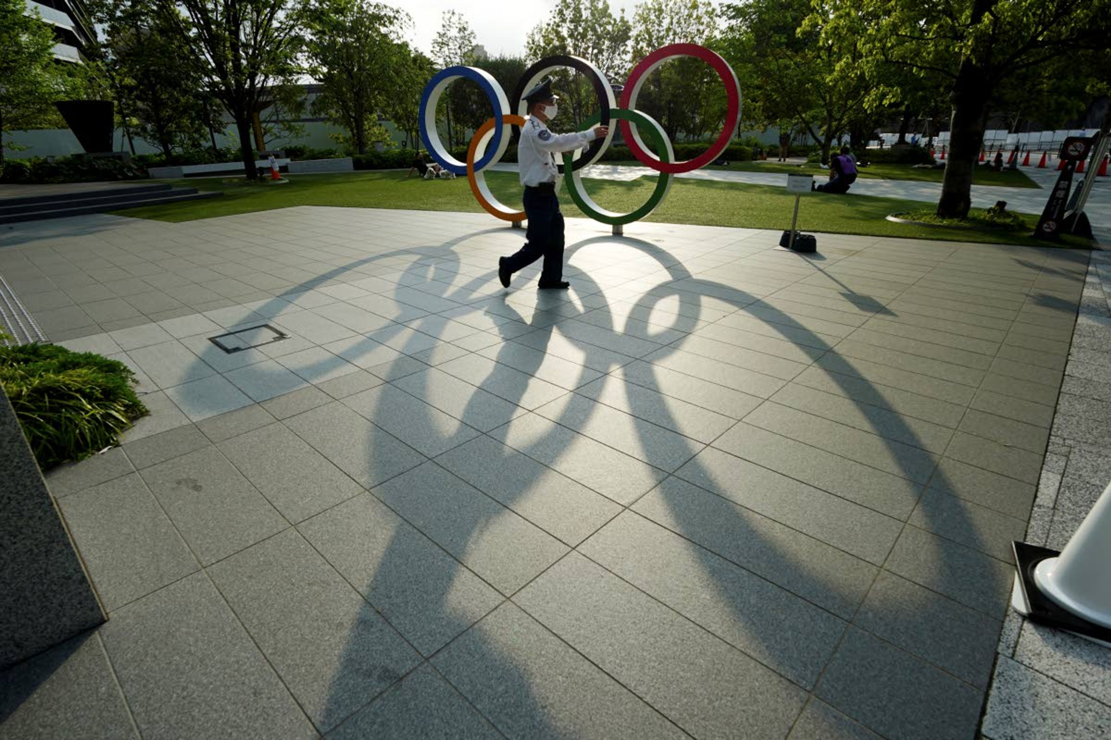 Associated PressA security guard wearing a protective mask to help curb the spread of the coronavirus walks in front of the Olympic Rings on May 9.