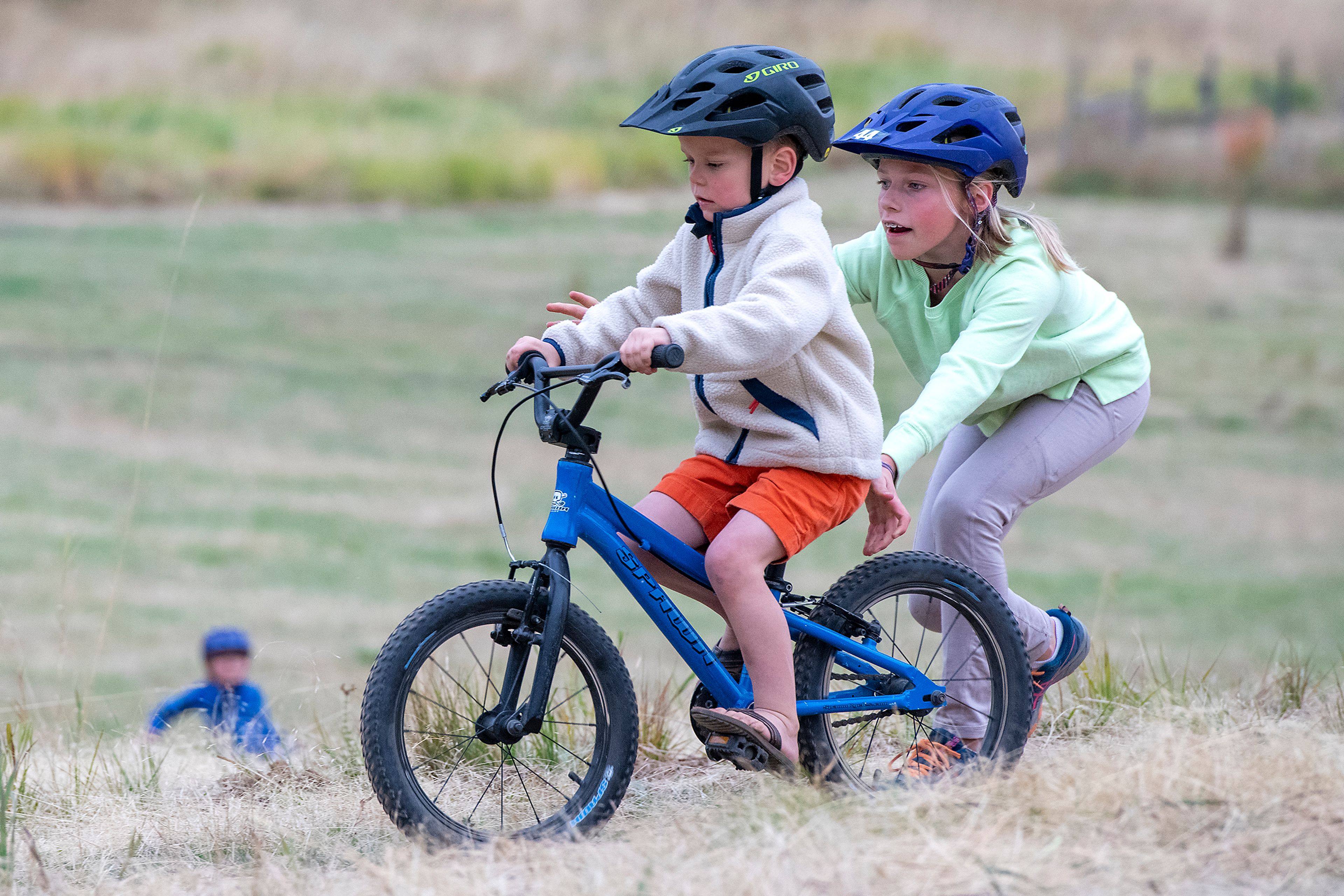 Lizzie Modad, 11, gives George Hoehn, 5, a boost up the hill while riding bikes on a new trail at Phillips Farm.