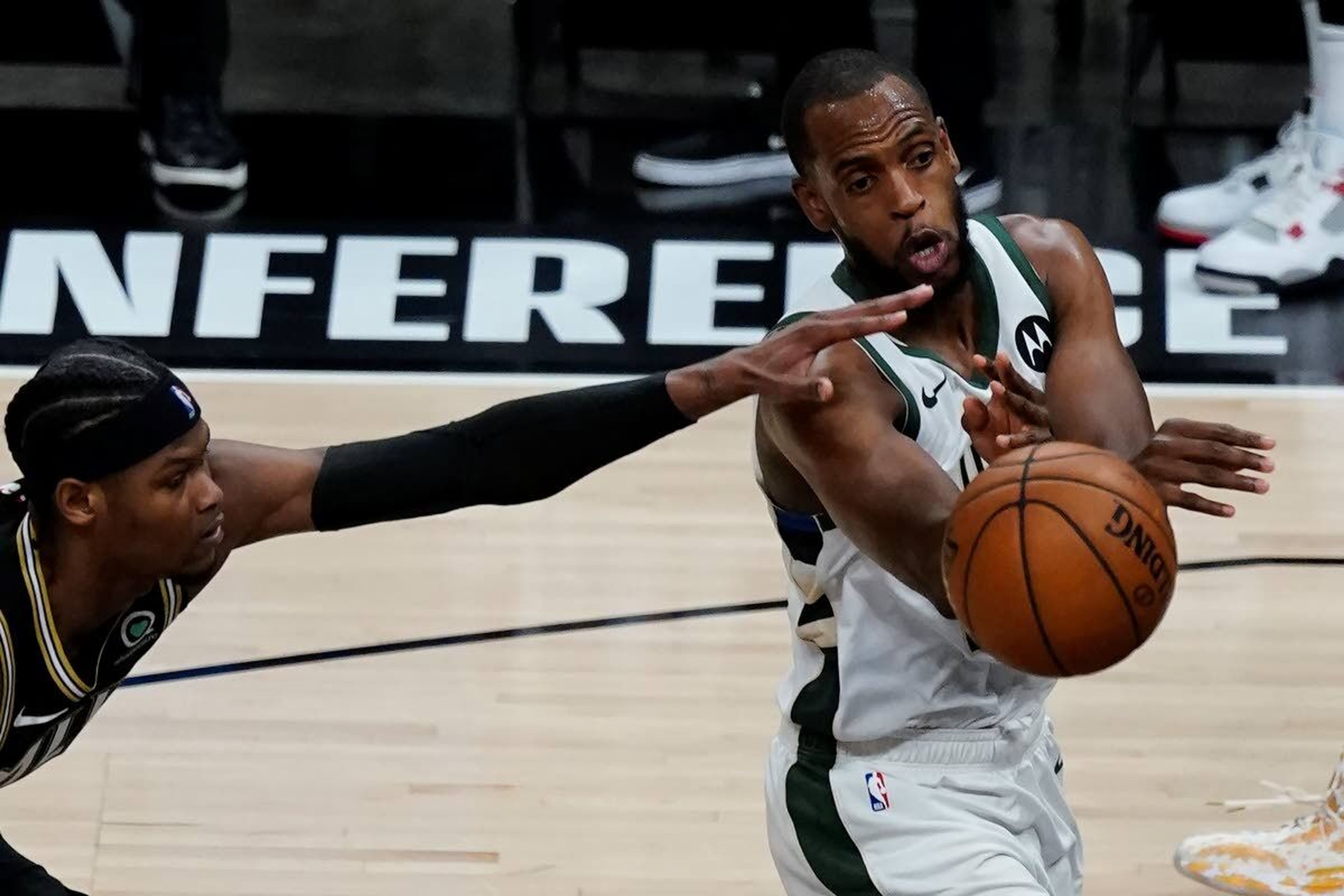 Milwaukee Bucks forward Khris Middleton, right, passes the ball as Atlanta Hawks forward Cam Reddish, left, defends during the second half in Game 6 of the Eastern Conference finals in the NBA basketball playoffs Saturday, July 3, 2021, in Atlanta. (AP Photo/John Bazemore)