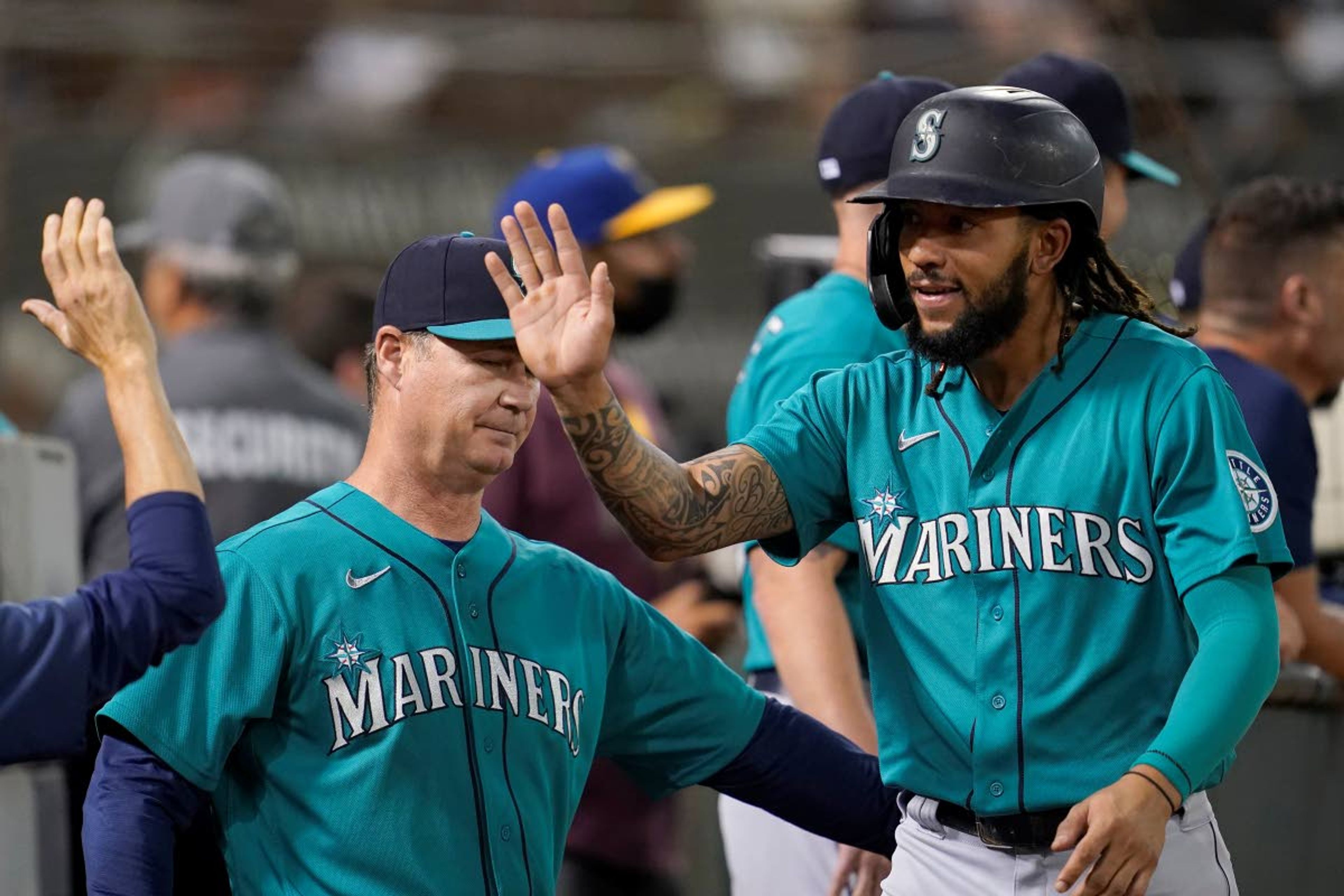 Mariners’ J.P. Crawford, right, is congratulated by manager Scott Servais, left, and teammates after scoring a run against the Athletics during the third inning of a game Monday in Oakland, Calif.