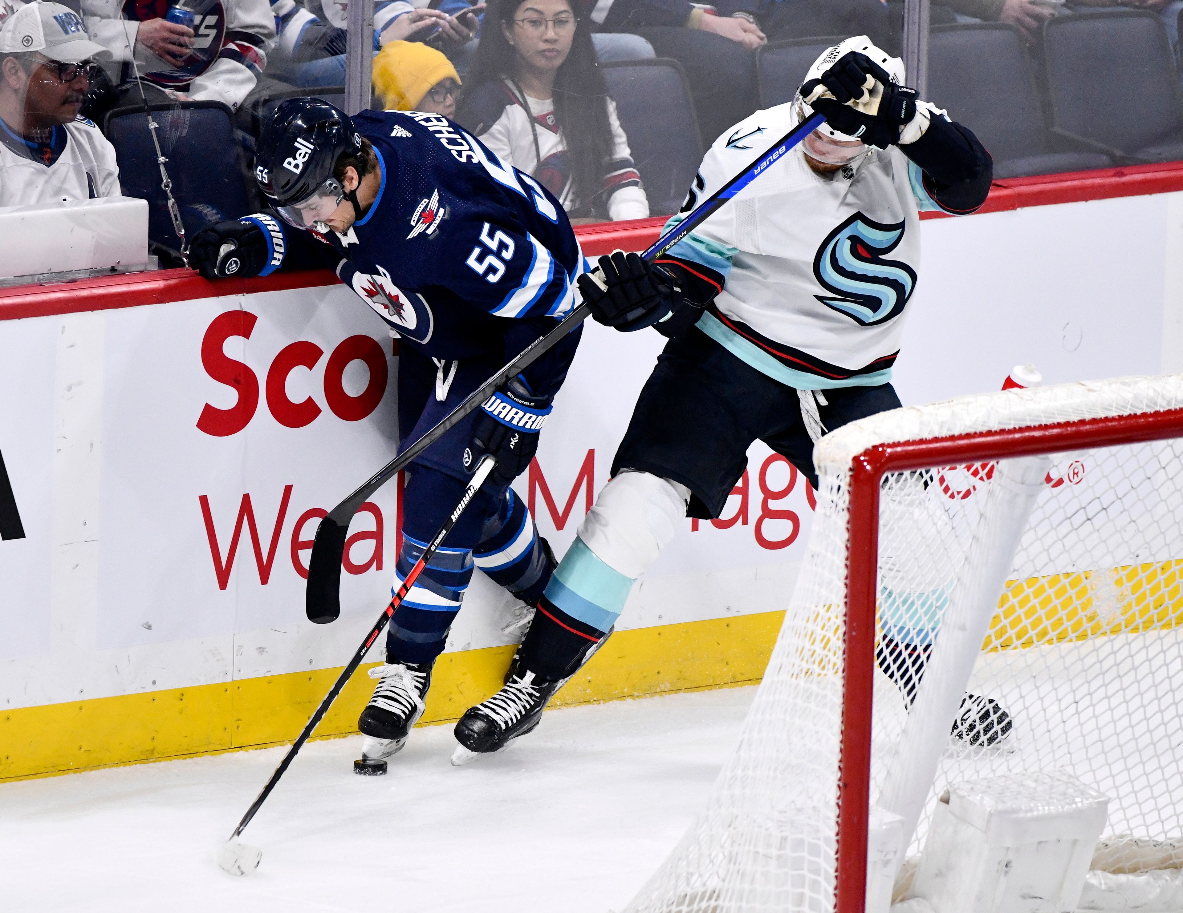 Seattle Kraken's Adam Larsson (6) and Winnipeg Jets' Mark Scheifele (55) battle for the puck during the first period of an NHL game in Winnipeg, Manitoba on Tuesday Feb. 14, 2023. (Fred Greenslade/The Canadian Press via AP)