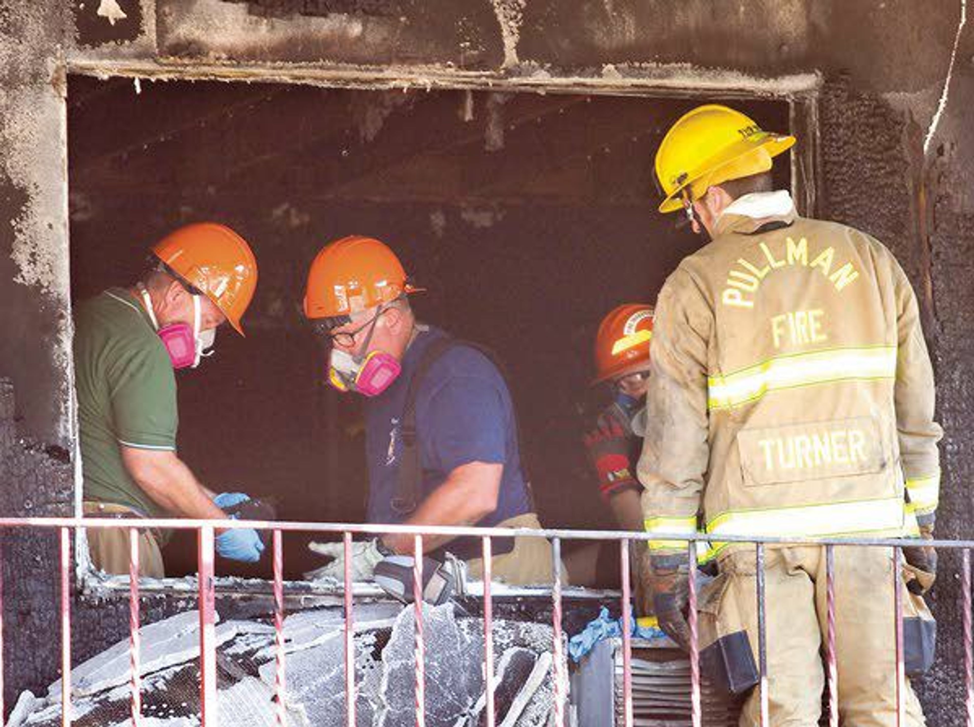 Investigators from the Pullman Fire Department and Washington State University Police Department work inside a room where a fire started at the American Travel Inn on Tuesday on south Grand Avenue in Pullman.