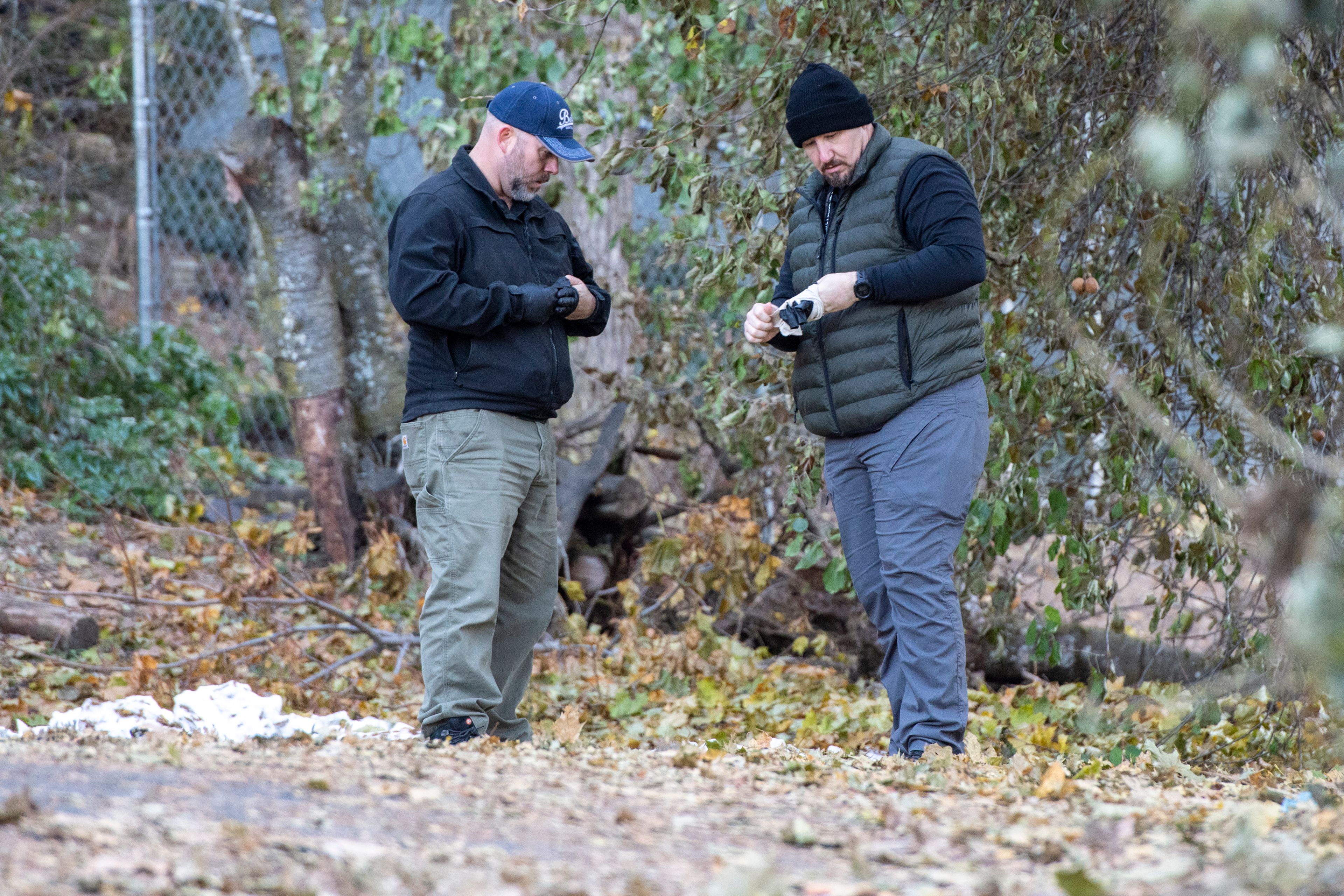 Officers investigate Monday in a parking lot behind the home where four University of Idaho students were stabbed in a quadruple homicide on King Road in Moscow.