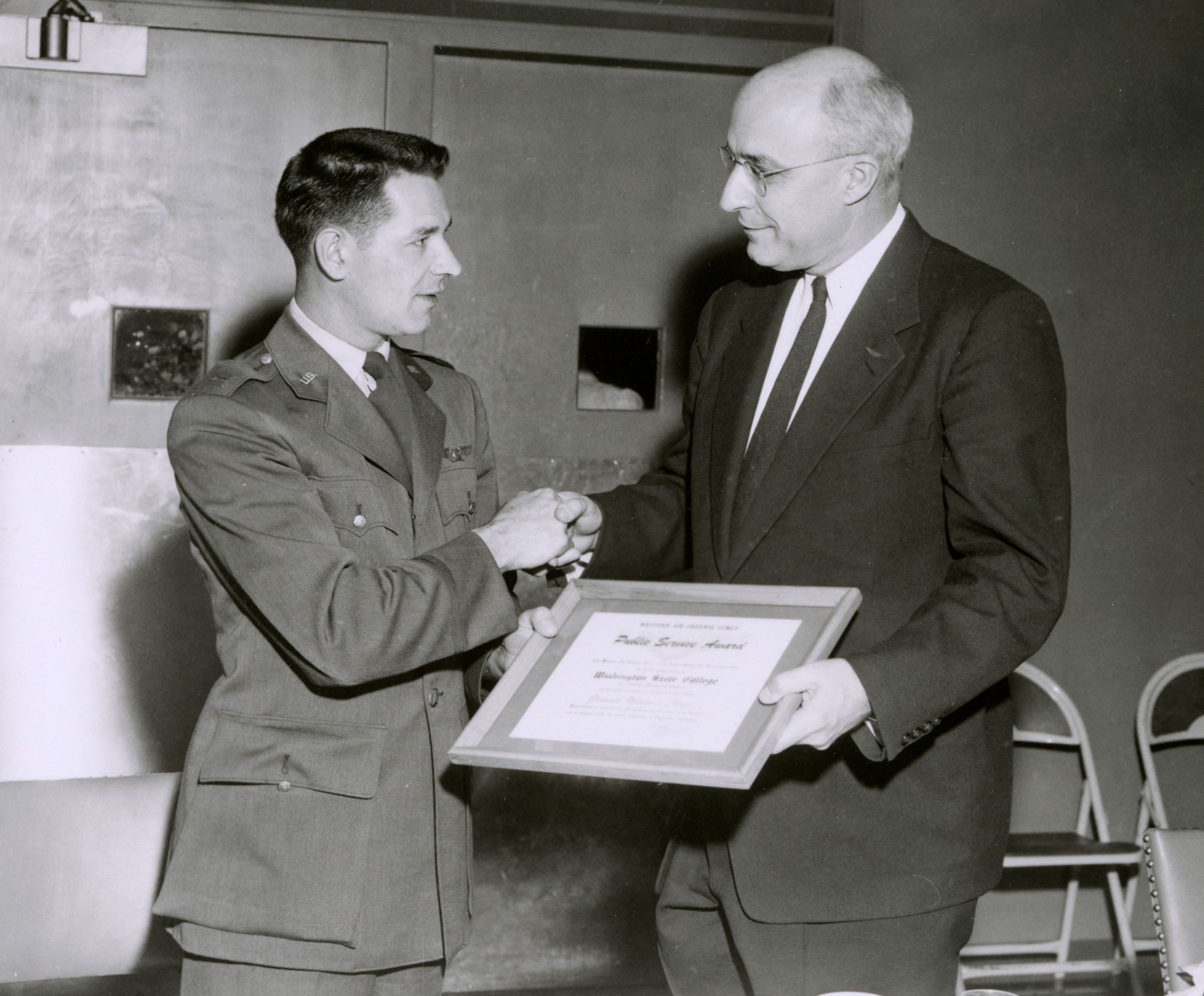 Captain Lowell Kneece, commander of the 4755th Ground Observer Squadron at Geiger Field, presents Washington State College President C. Clement French with a certificate of appreciation for WSC’s efforts in November 1954.