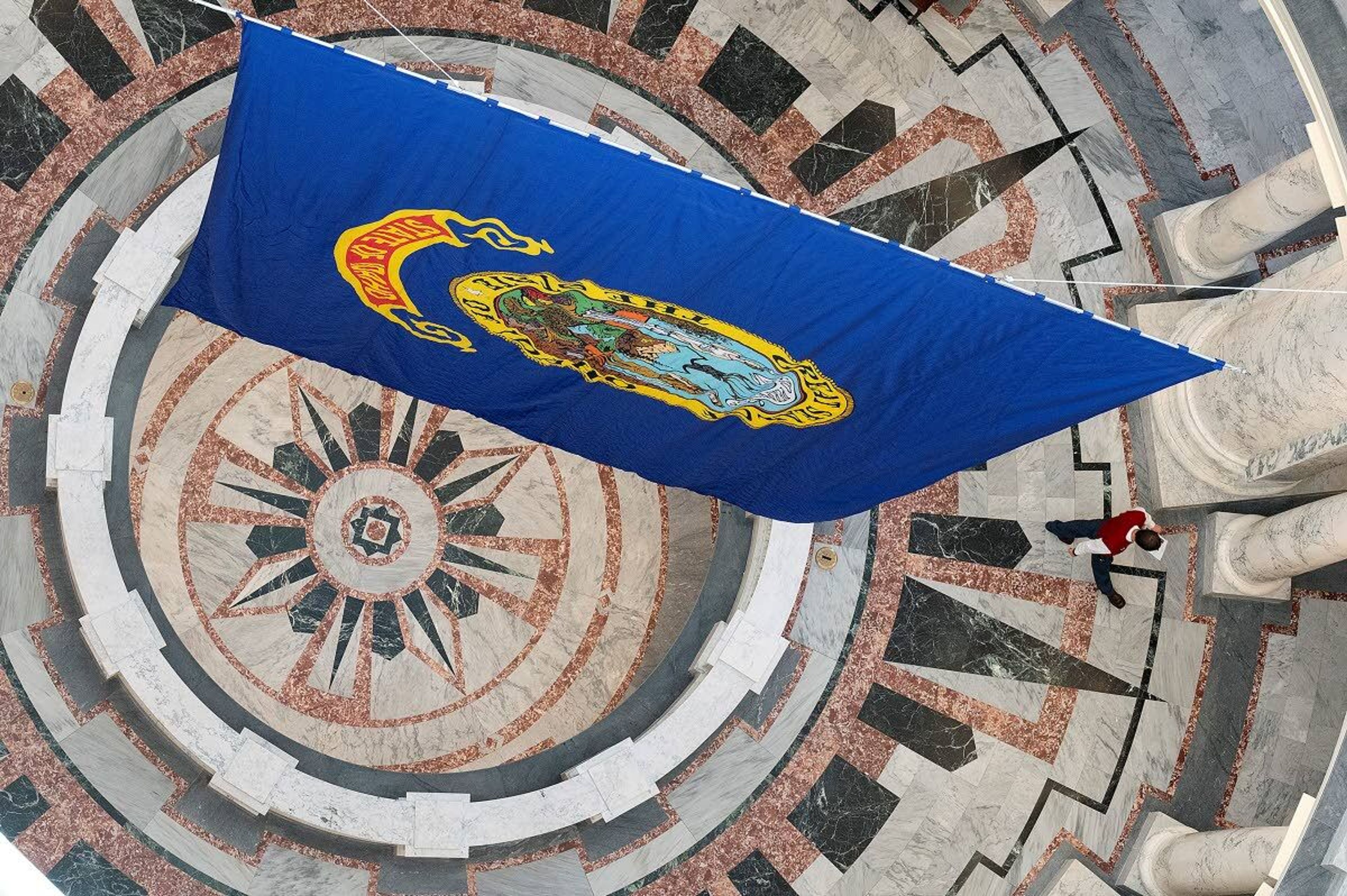 The Idaho state flag hangs from center of the rotunda as a page walks by on the second floor earlier this month at the Idaho Capitol in Boise.