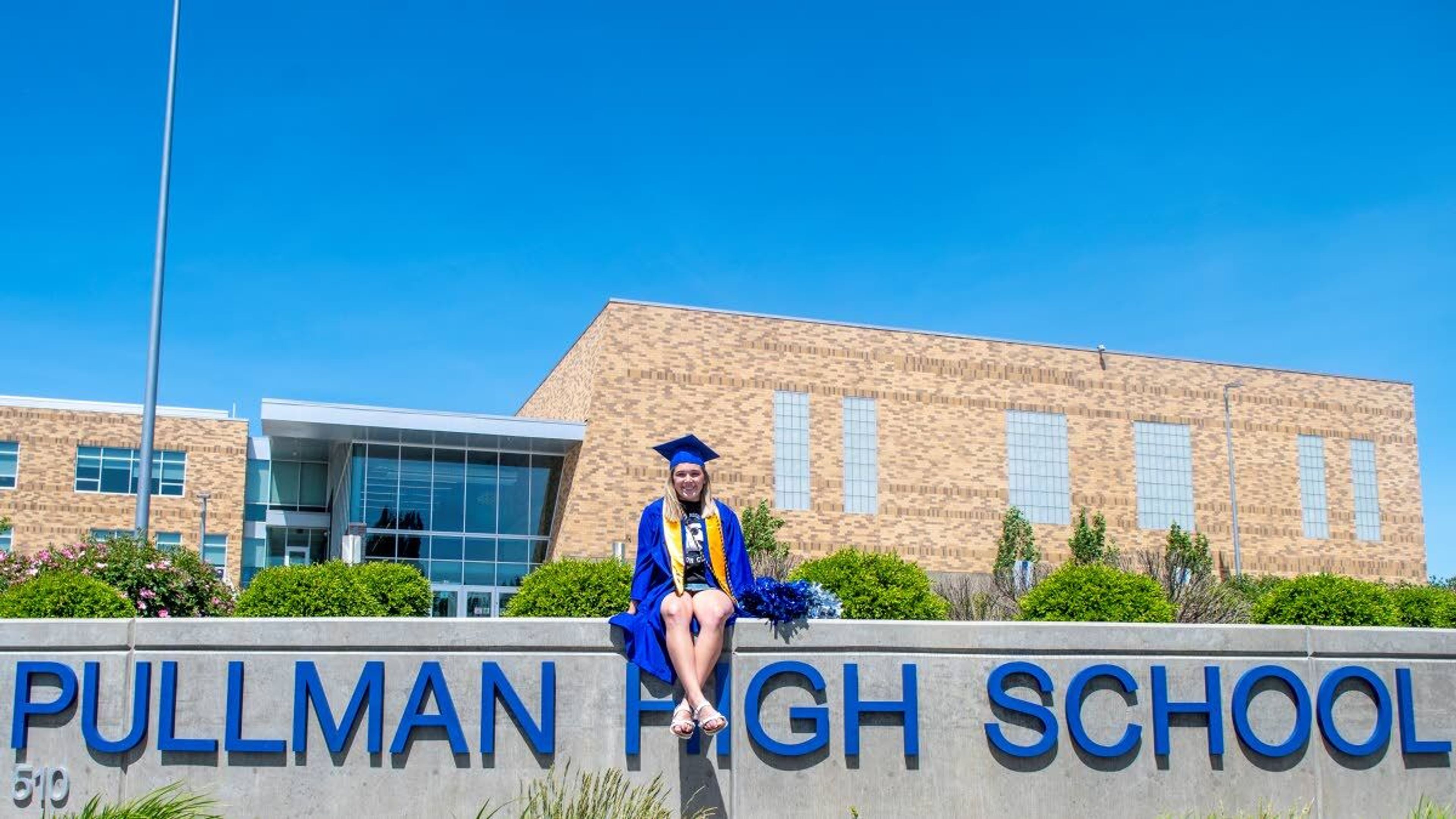 In her graduation regalia, senior Hannah Talbot poses for a picture in front of Pullman High School. Talbot is a honor graduate who plans to pursue a degree in elementary education.