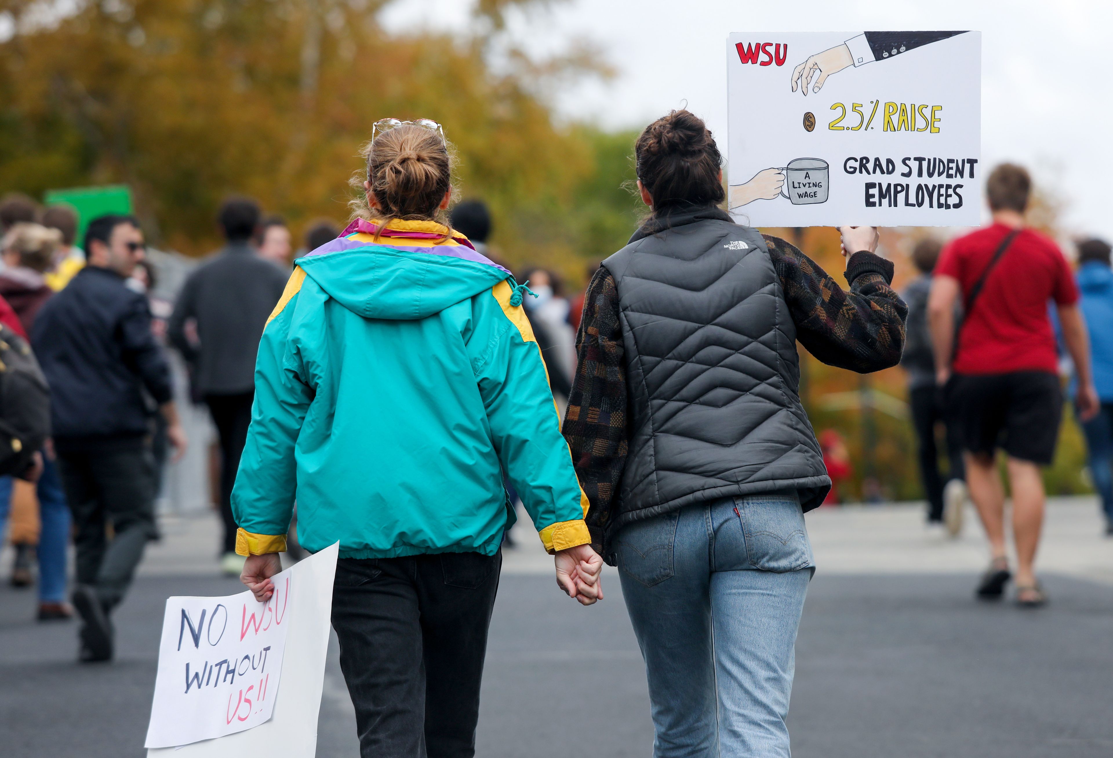 Natalie Yaw, left, a third-year PhD student in chemistry at Washington State University, and McKinley Nevins, a fourth-year PhD student in biological sciences, carry signs as they walk back from a rally supporting contract negotiations for Academic Student Employees on Wednesday in Pullman. The group marched down Glenn Terrell Mall to the French Administration Building after listening to a series of student speakers.