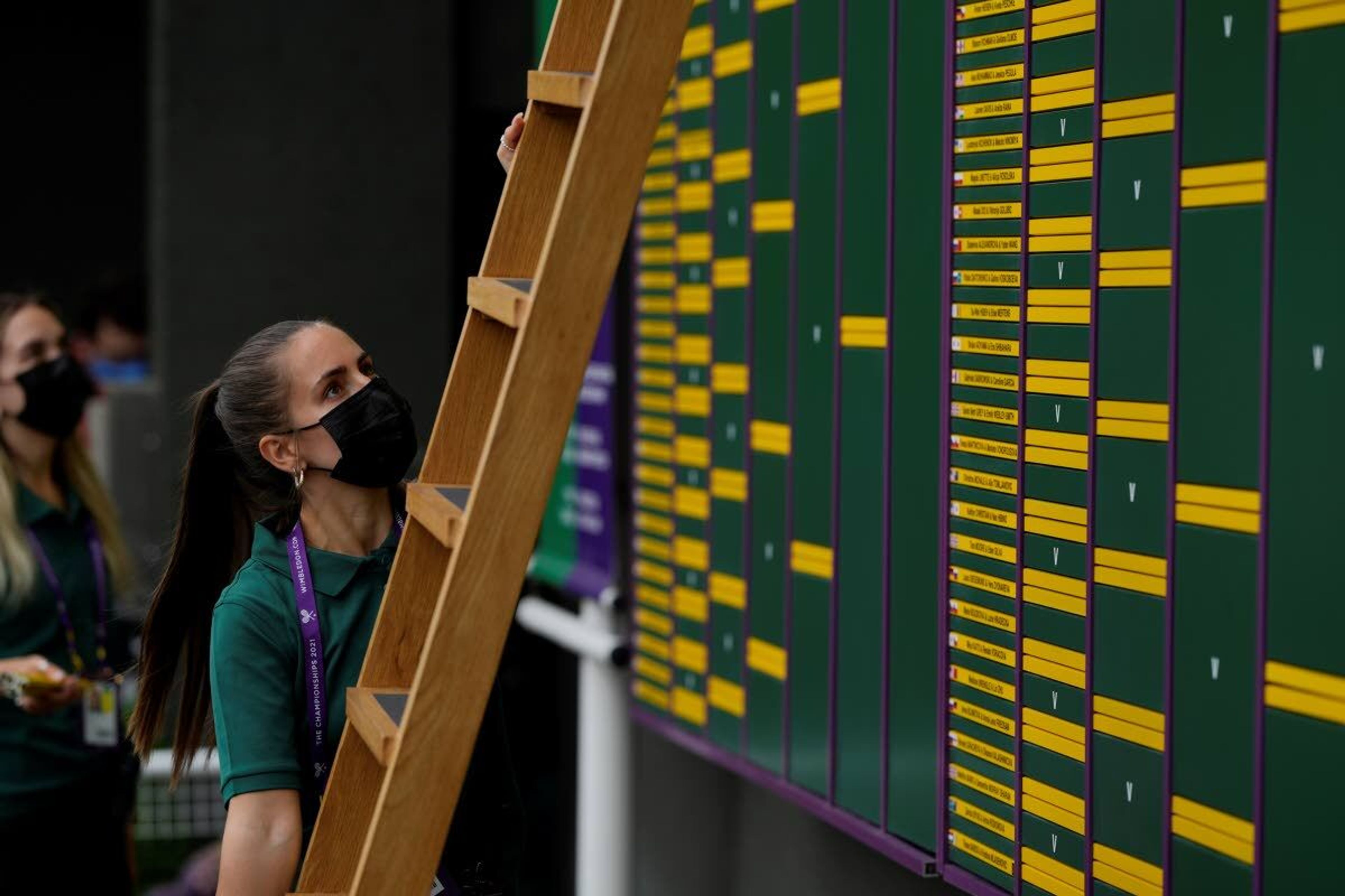 A member of staff places information on the scoreboard in the grounds of the Wimbledon Tennis Championships in London, Thursday July 1, 2021. (AP Photo/Alastair Grant)