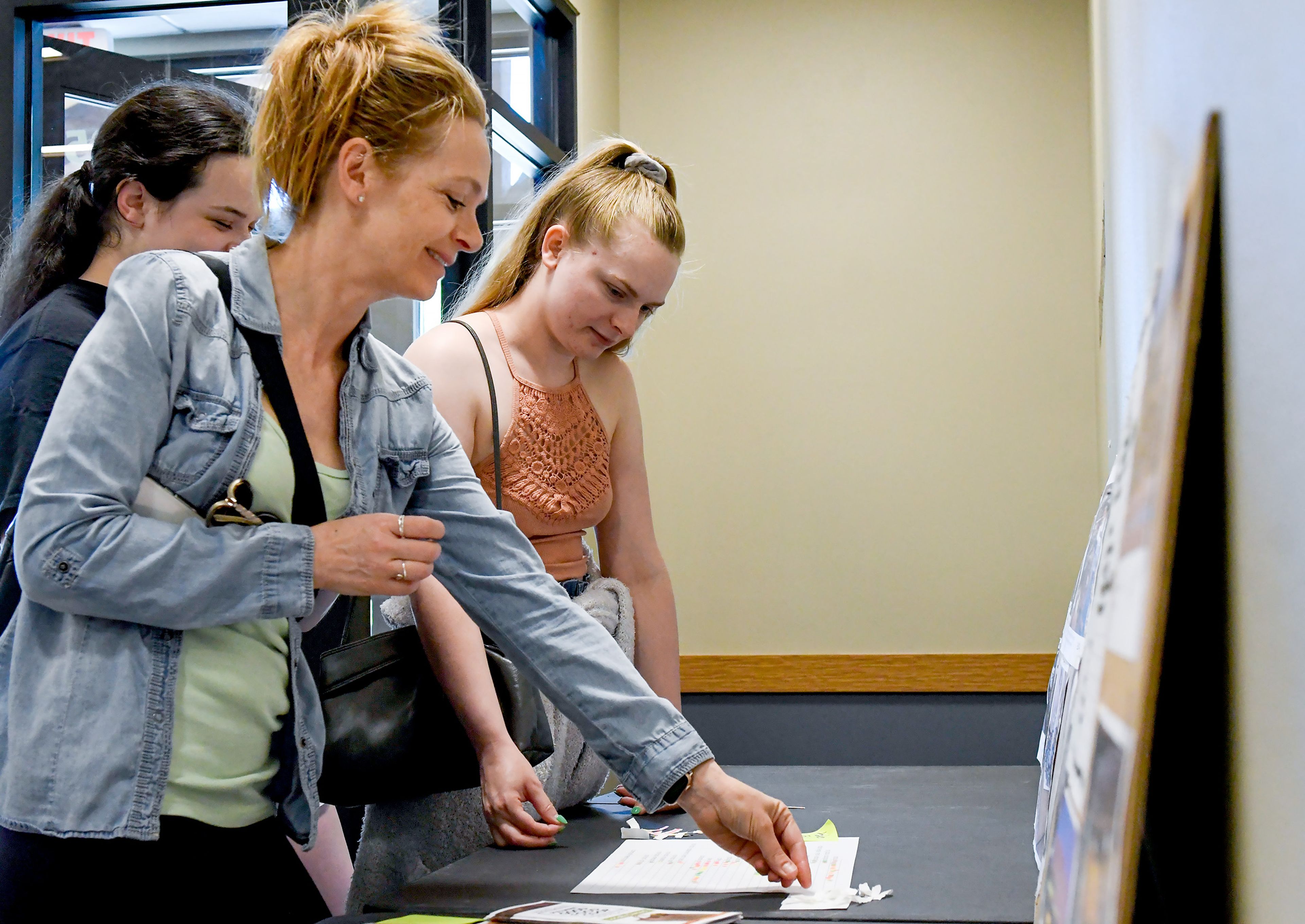 Claudia Mickas, front, of Pullman, places a vote on a sticker survey for future favorite sections in the Pullman Good Food Co-op alongside daughters Caroline Mickas, left, and Abigail Mickas, back, at the co-op’s open house on Wednesday in Pullman.