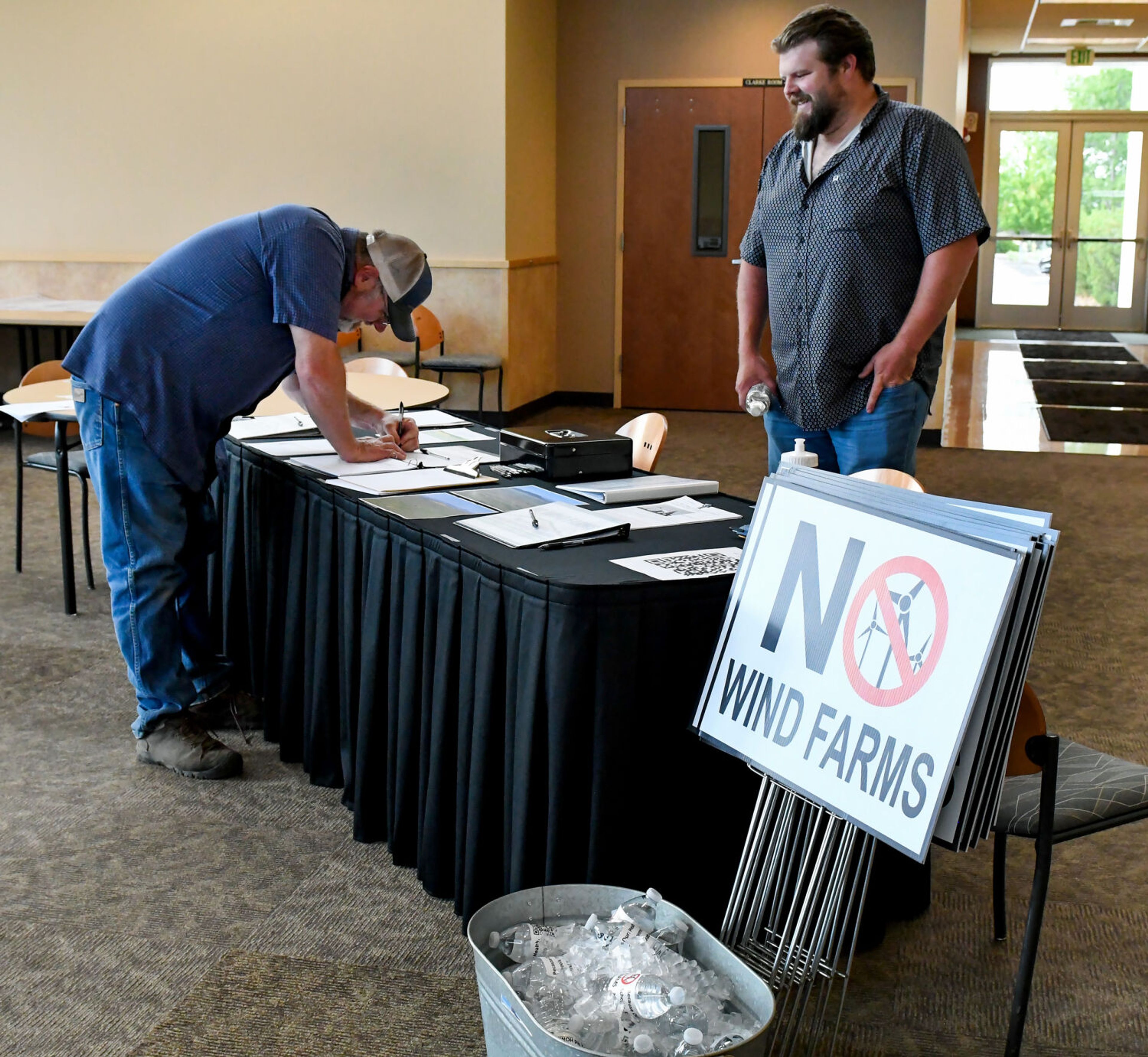 Shane Riebold, right, who lives near the north base of Kamiak Butte, mans a sign-in table at the Save the Palouse public meeting on Thursday in Pullman.