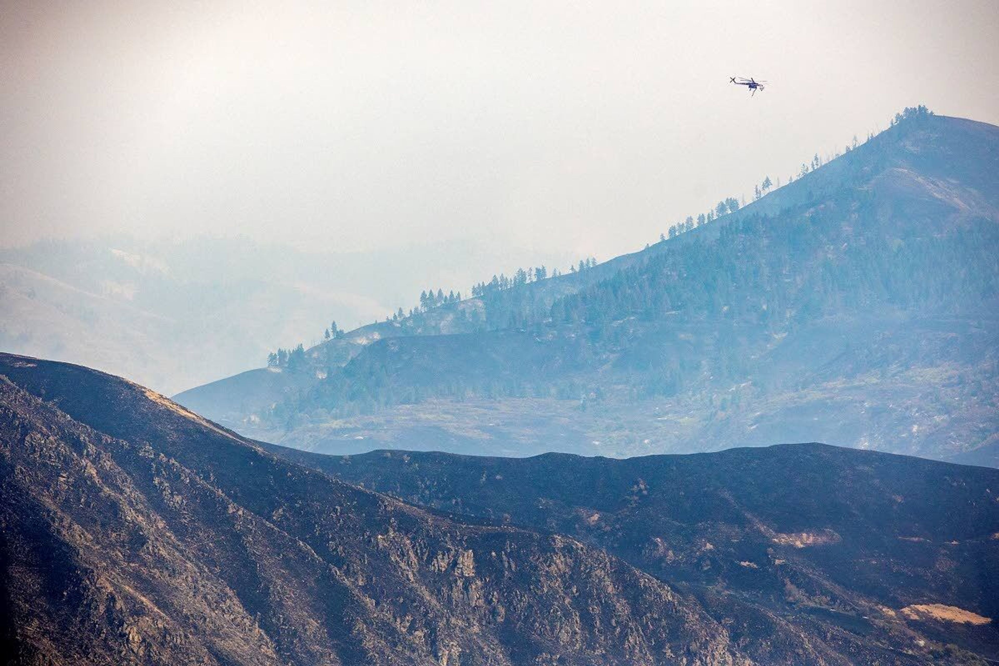 A helicopter moves above the charred hillsides of the Snake River Complex fire on Saturday.