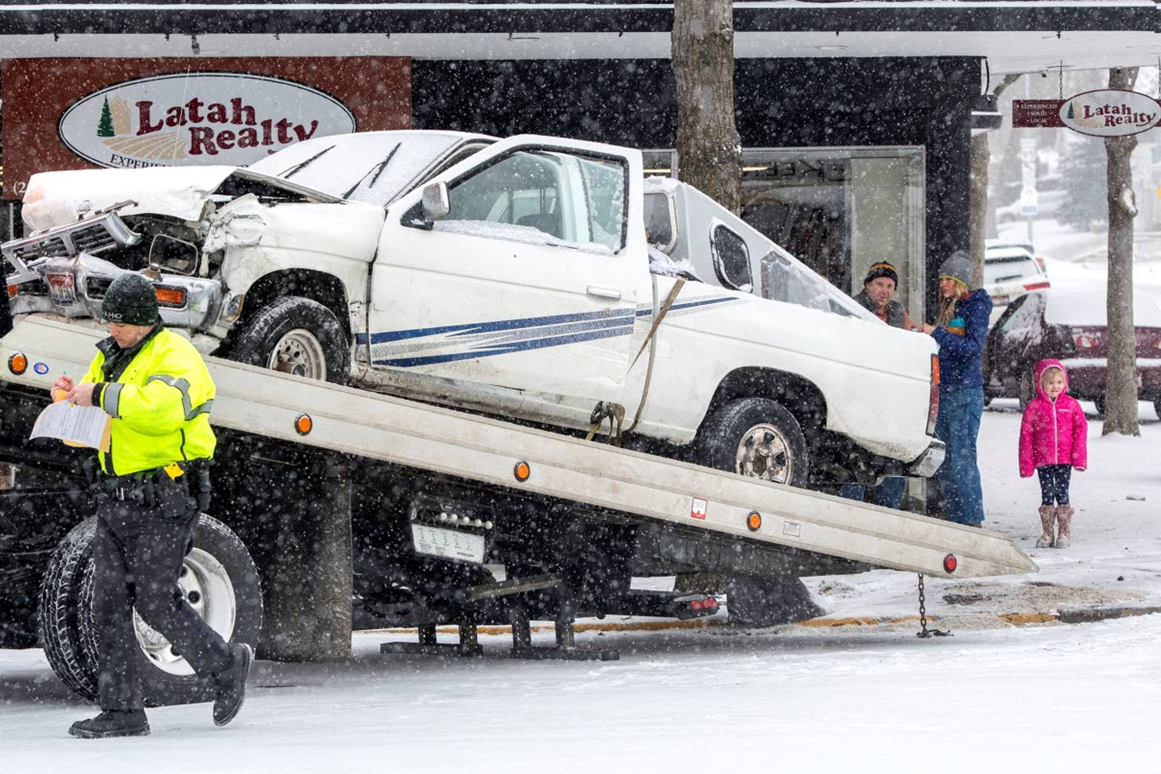 Passersby examine the damage of a truck while an Idaho State Police officer fills out a report Friday morning after the driver was arrested following a two-car crash at the intersection of Washington and Third streets in downtown Moscow. ,