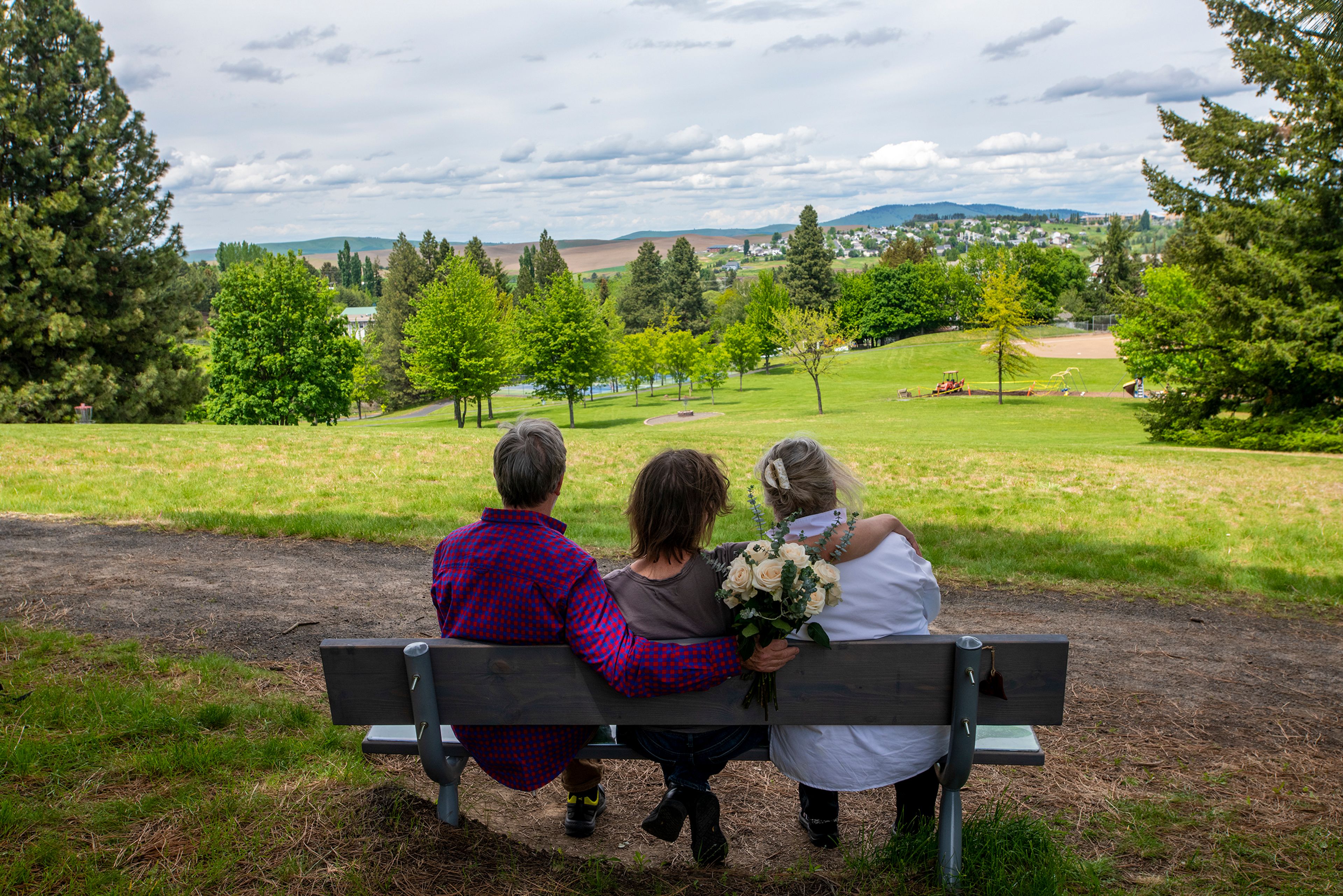 Cliff Moore, from left, Ann Saberi and Mea Moore sit on the Cliffy Moore memorial bench overlooking Sunnyside Park in Pullman in June