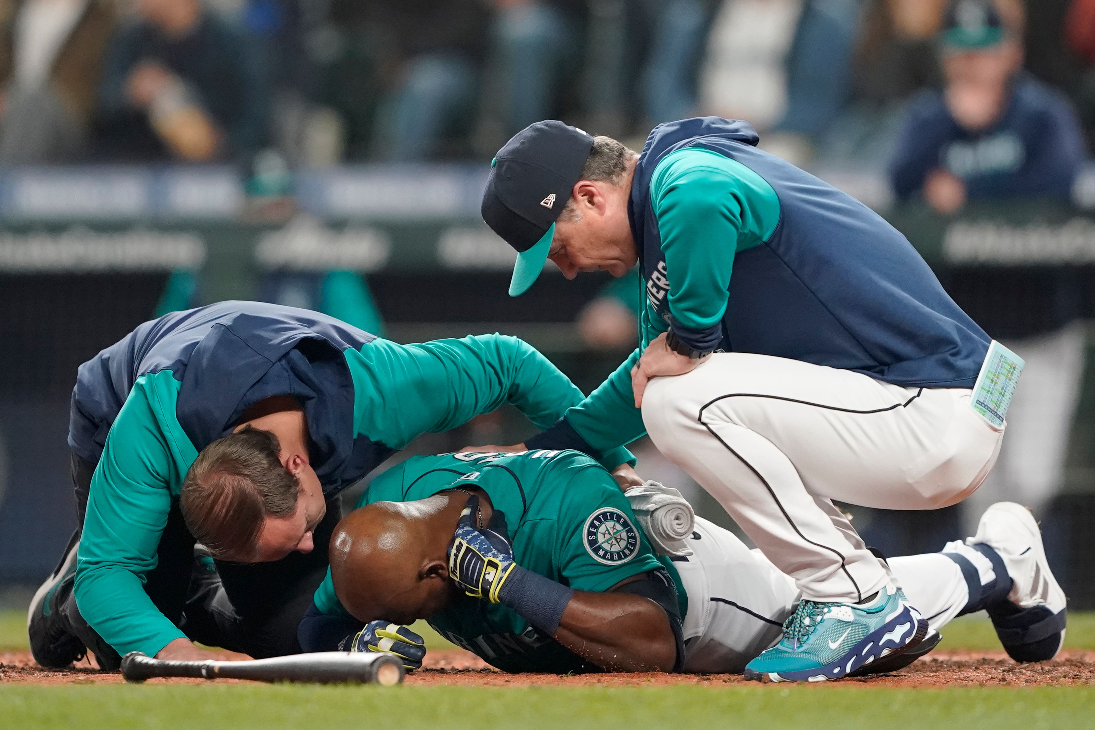 Seattle Mariners' Justin Upton, center, points to where he was hit by a pitch during the fifth inning of a baseball game against the Los Angeles Angels as he is examined by a trainer, left, and manager Scott Servais, right, Friday, June 17, 2022, in Seattle. Upton left the game after the injury. (AP Photo/Ted S. Warren)