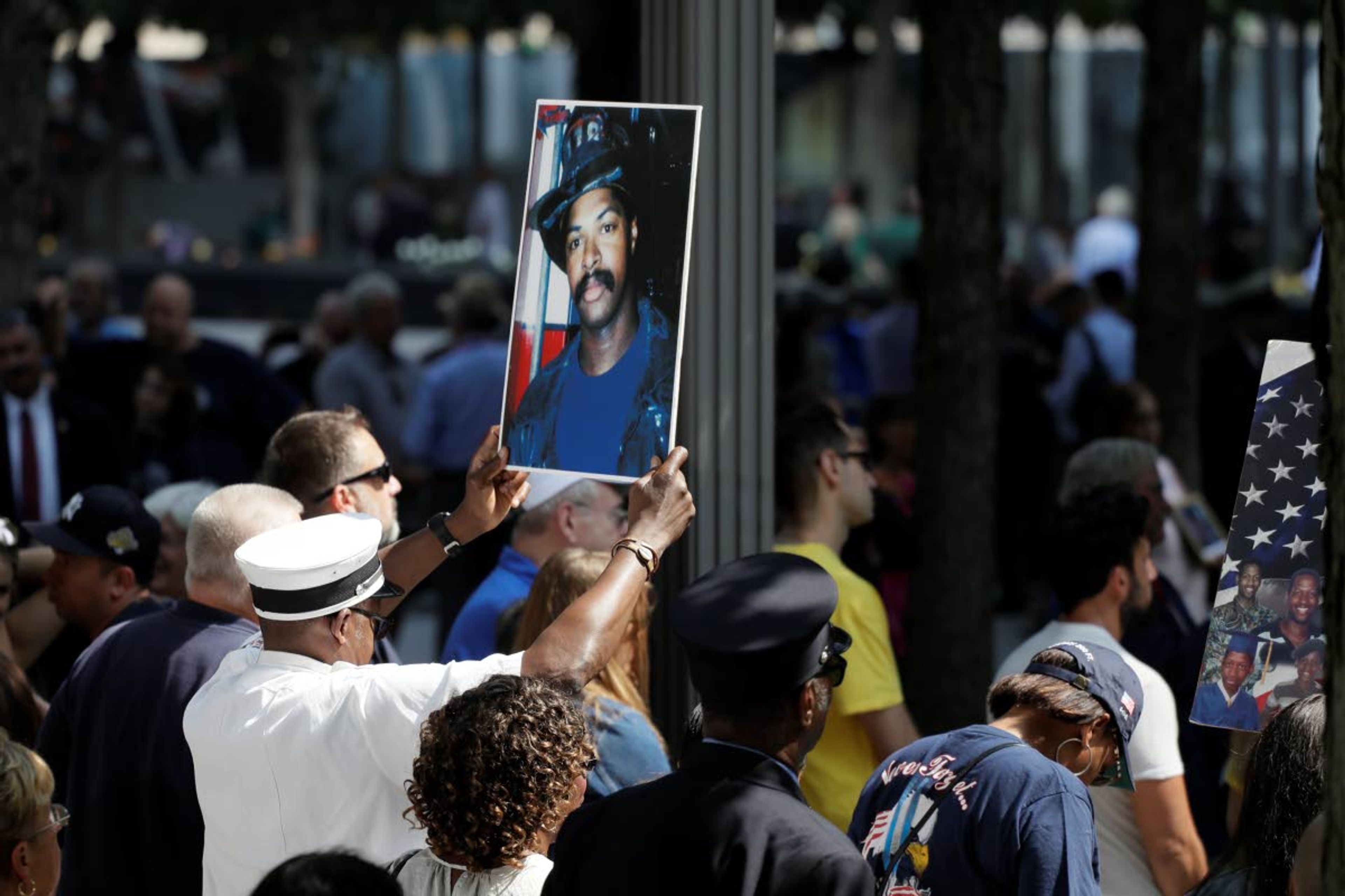 FILE - In this Sept. 11, 2019, file photo, a photograph of fallen firefighter Leon Smith, Jr. is held up during a ceremony marking the 18th anniversary of the attacks of Sept. 11, 2001 at the National September 11 Memorial, in New York. The coronavirus pandemic has reshaped how the U.S. is observing the anniversary of 9/11. The terror attacks' 19th anniversary will be marked Friday, Sept. 11, 2020, by dueling ceremonies at the Sept. 11 memorial plaza and a corner nearby in New York. (AP Photo/Mark Lennihan, File)