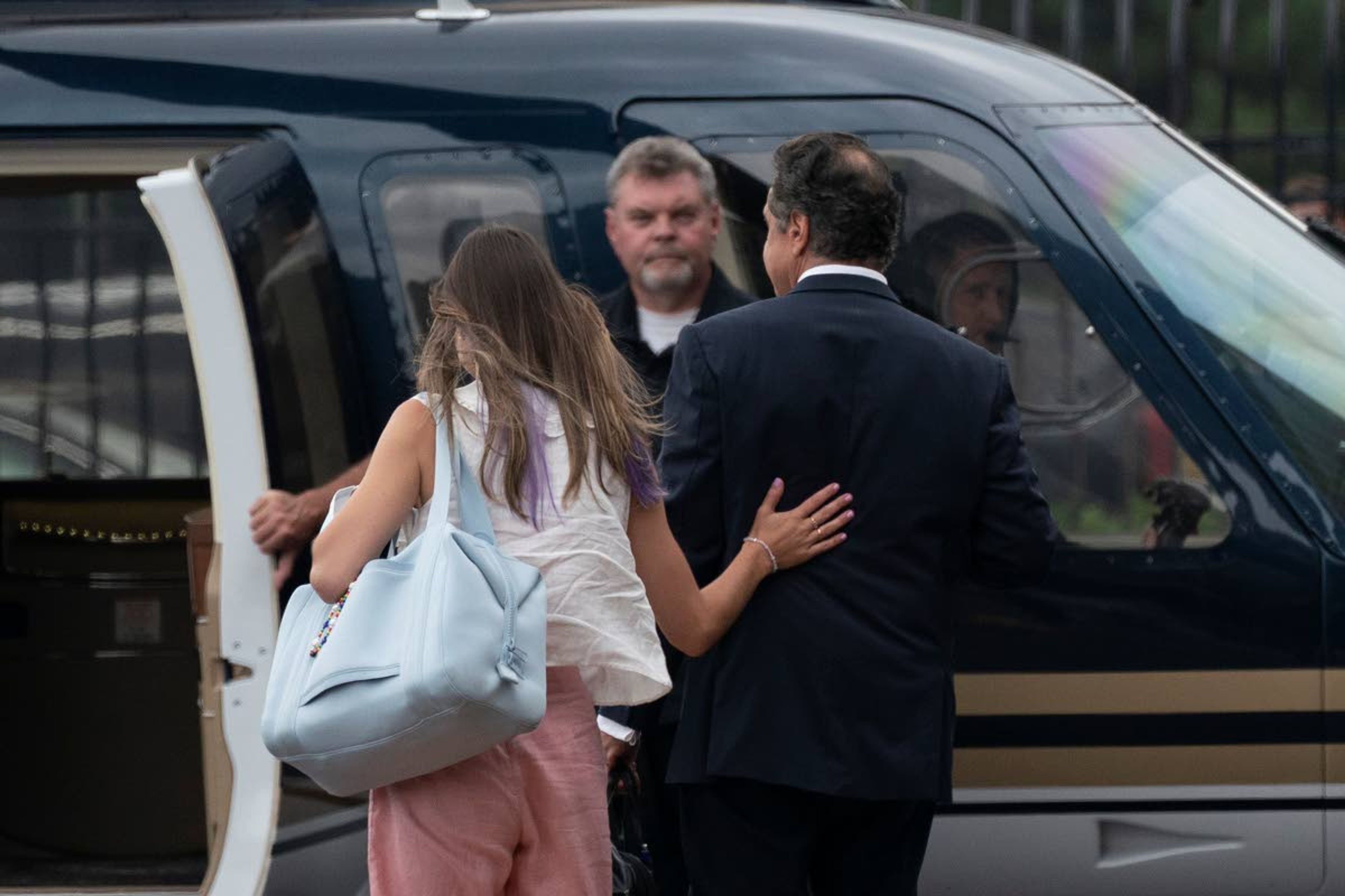 Michaela Cuomo, Andrew Cuomo's daughter, left, rests her hand on the back of her father, New York Gov. Andrew Cuomo as they take a helicopter flight from a Manhattan heliport, Tuesday, Aug. 10, 2021 in New York. Cuomo says he will resign over a barrage of sexual harassment allegations. The three-term Democratic governor’s decision, which will take effect in two weeks, was announced Tuesday as momentum built in the Legislature to remove him by impeachment. (AP Photo/Mark Lennihan)