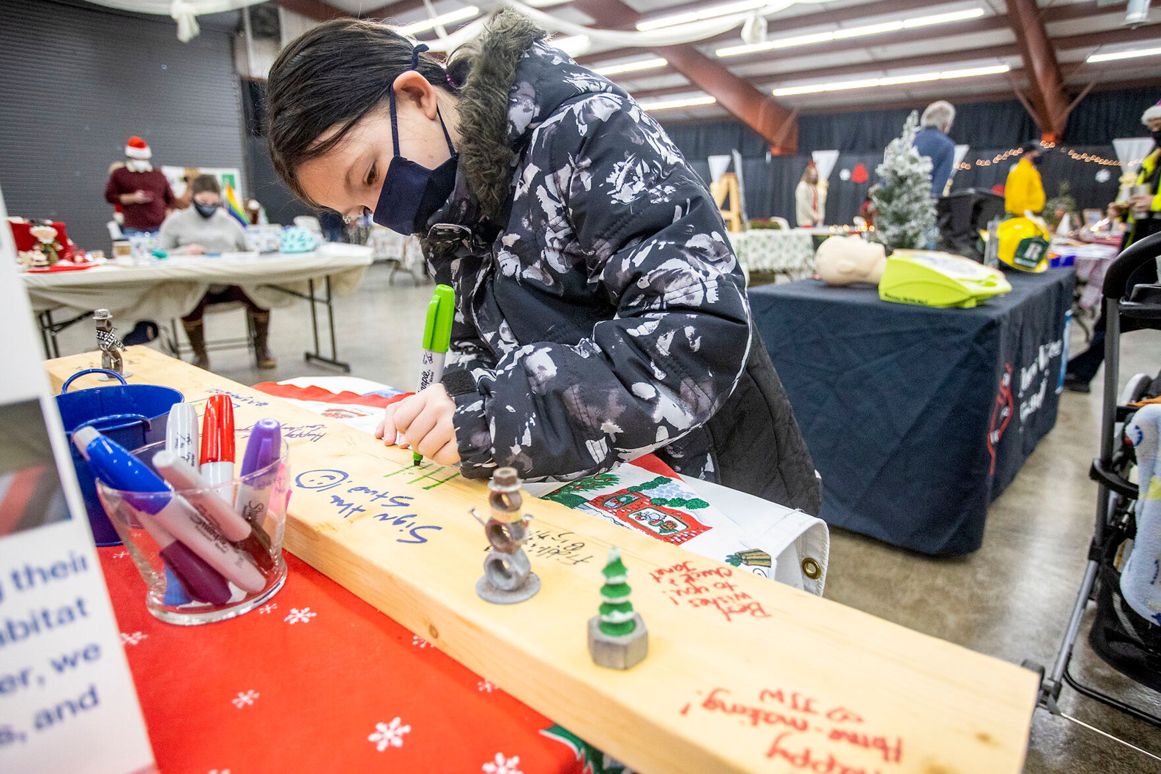 Amelia Turner, 7, of Moscow, writes “Hi!” On a piece of wood that will go in a families new home at the Habitat for Humanity booth at the Alternative Giving Market in Moscow on Saturday.