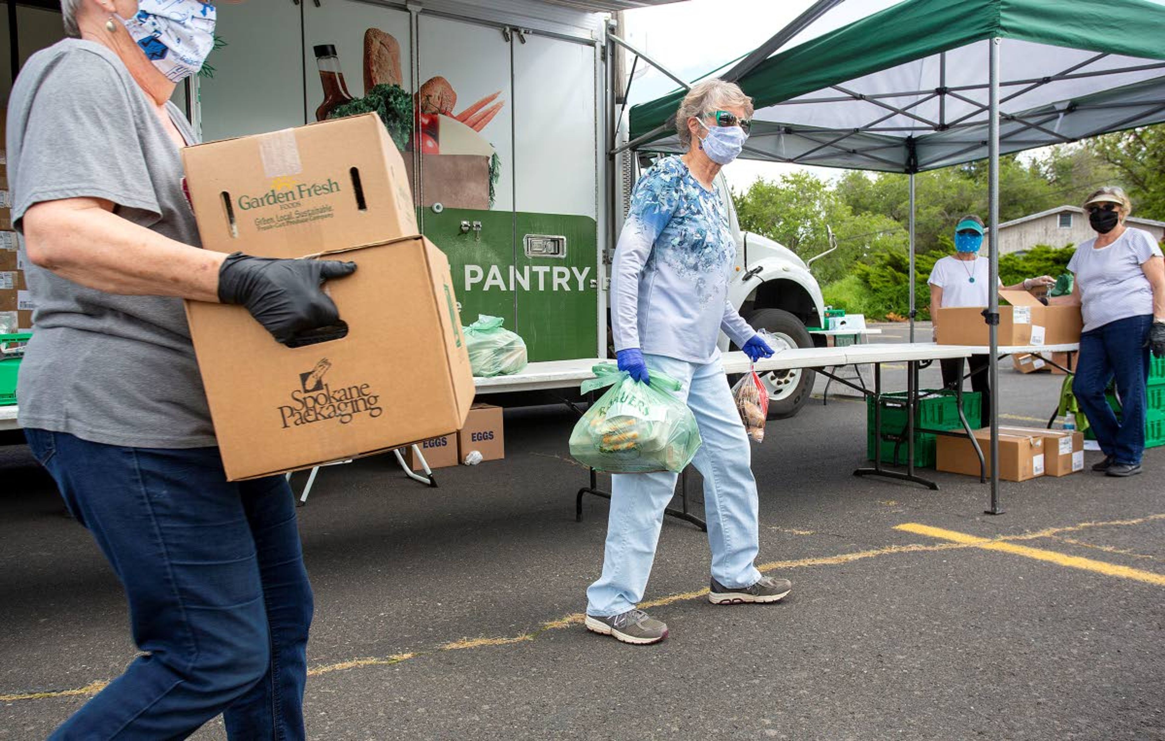 Susan Bohm, center, and other volunteers prepare to load food into a resident’s car during a free food distribution on Wednesday at Trinity Lutheran Church in Pullman. The event was organized by the church in cooperation with 2nd Harvest from Spokane.